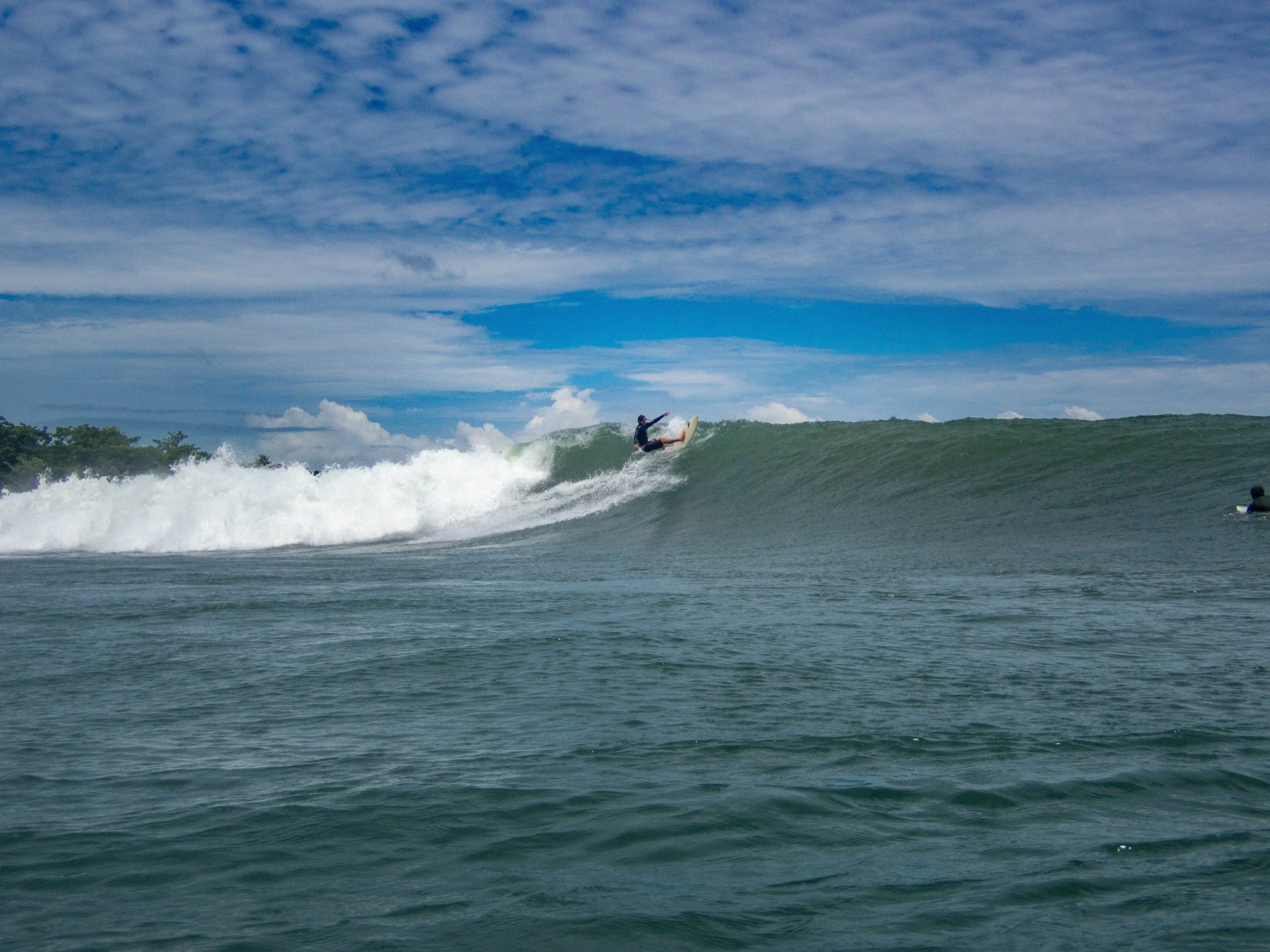 Surfer riding a large wave in the ocean under a cloudy sky