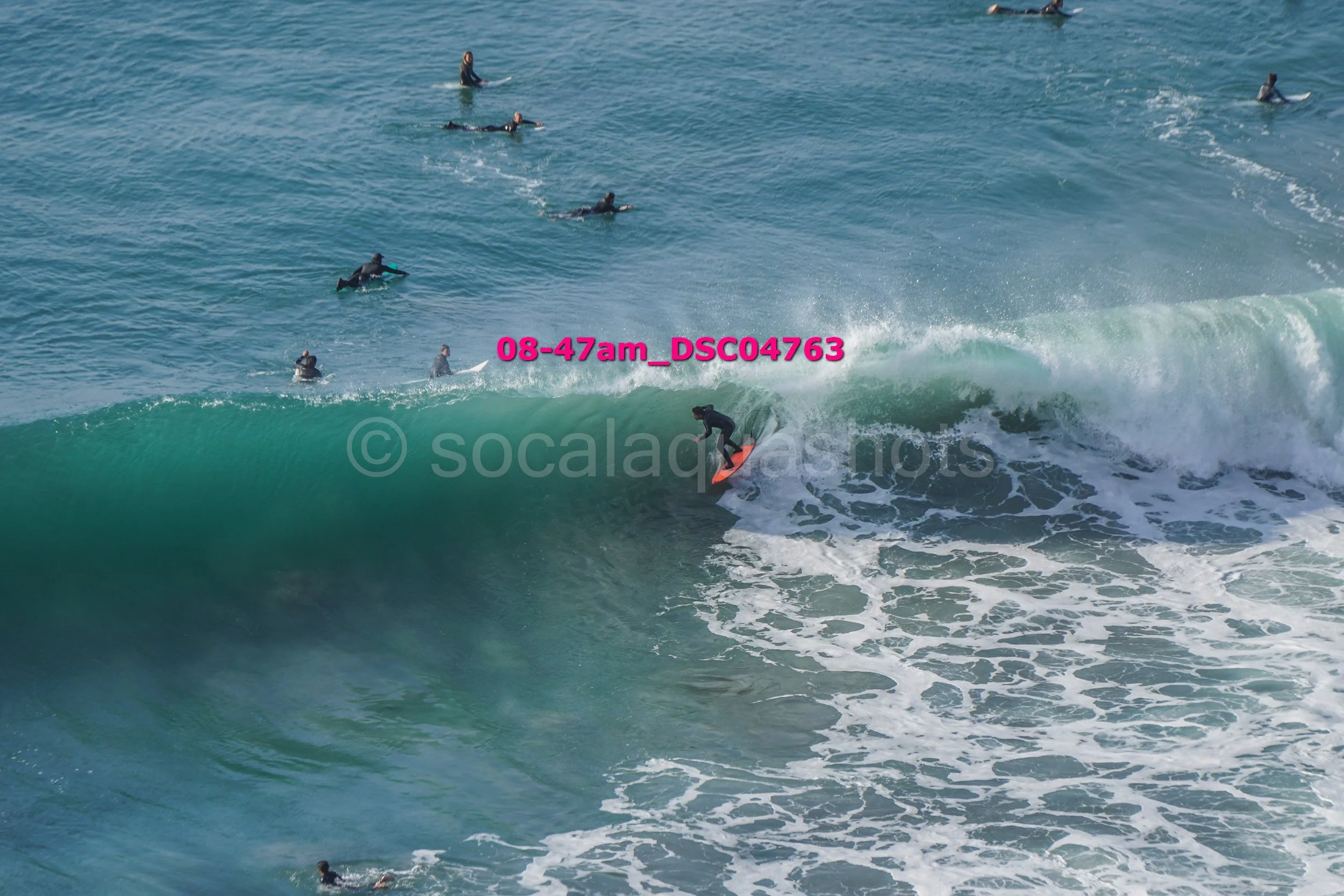 Surfer riding a wave with several surfers in the background in the ocean.