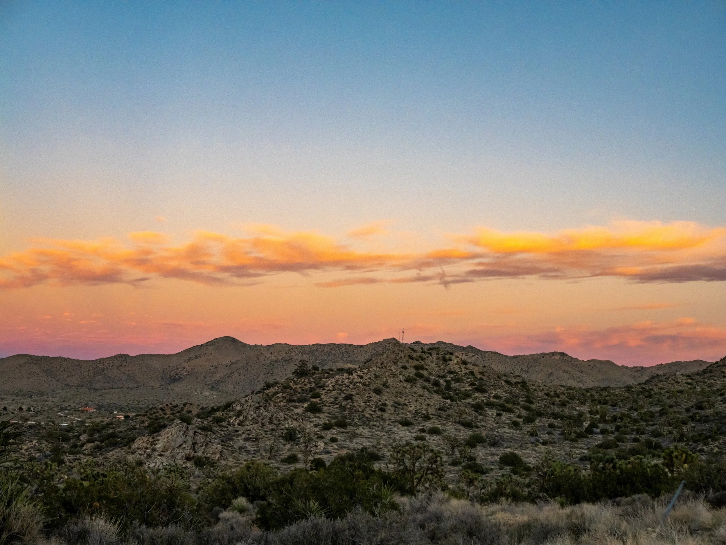 Sunset over desert mountains with a colorful sky of pink, orange, and blue.