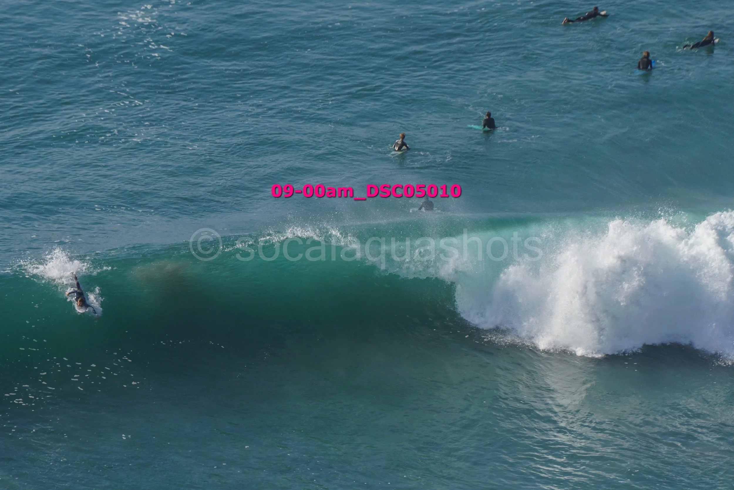 A person surfing a wave in the ocean with other surfers and surfers in the water in the background.