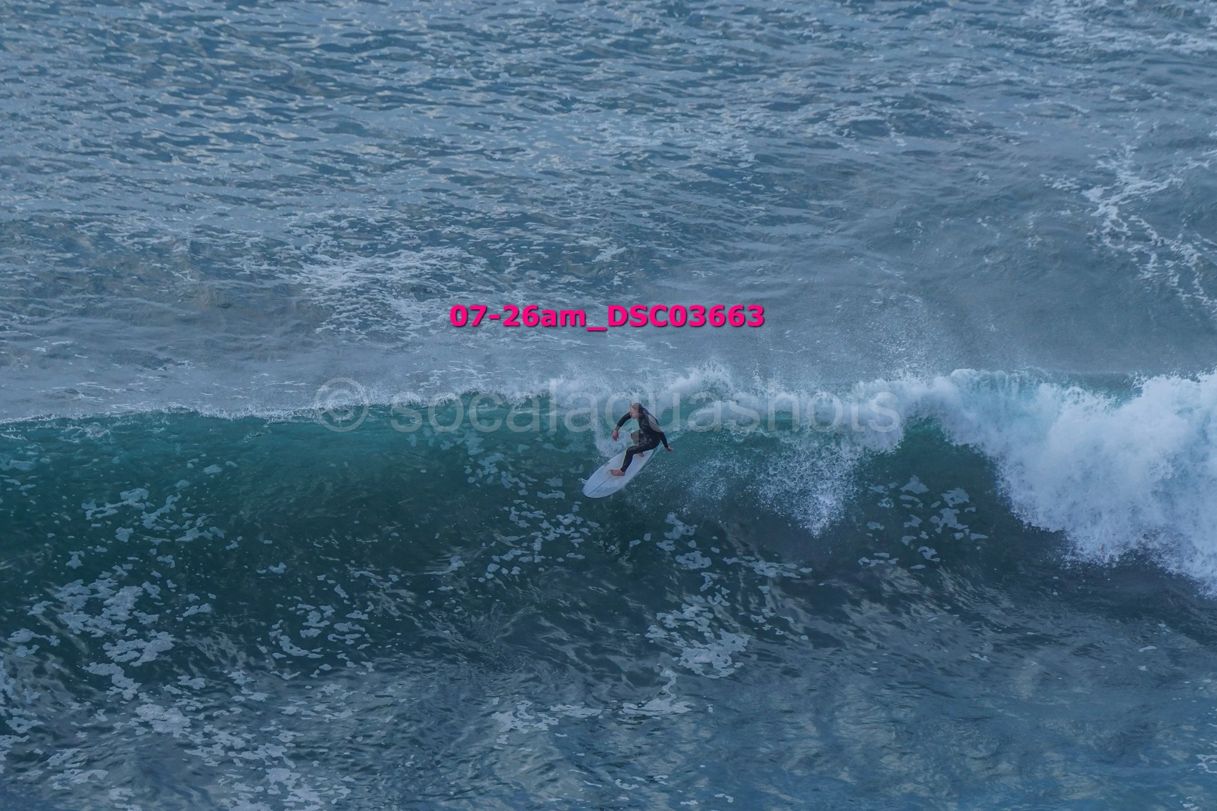 A surfer riding a wave in the ocean during daylight, with water splashing around.
