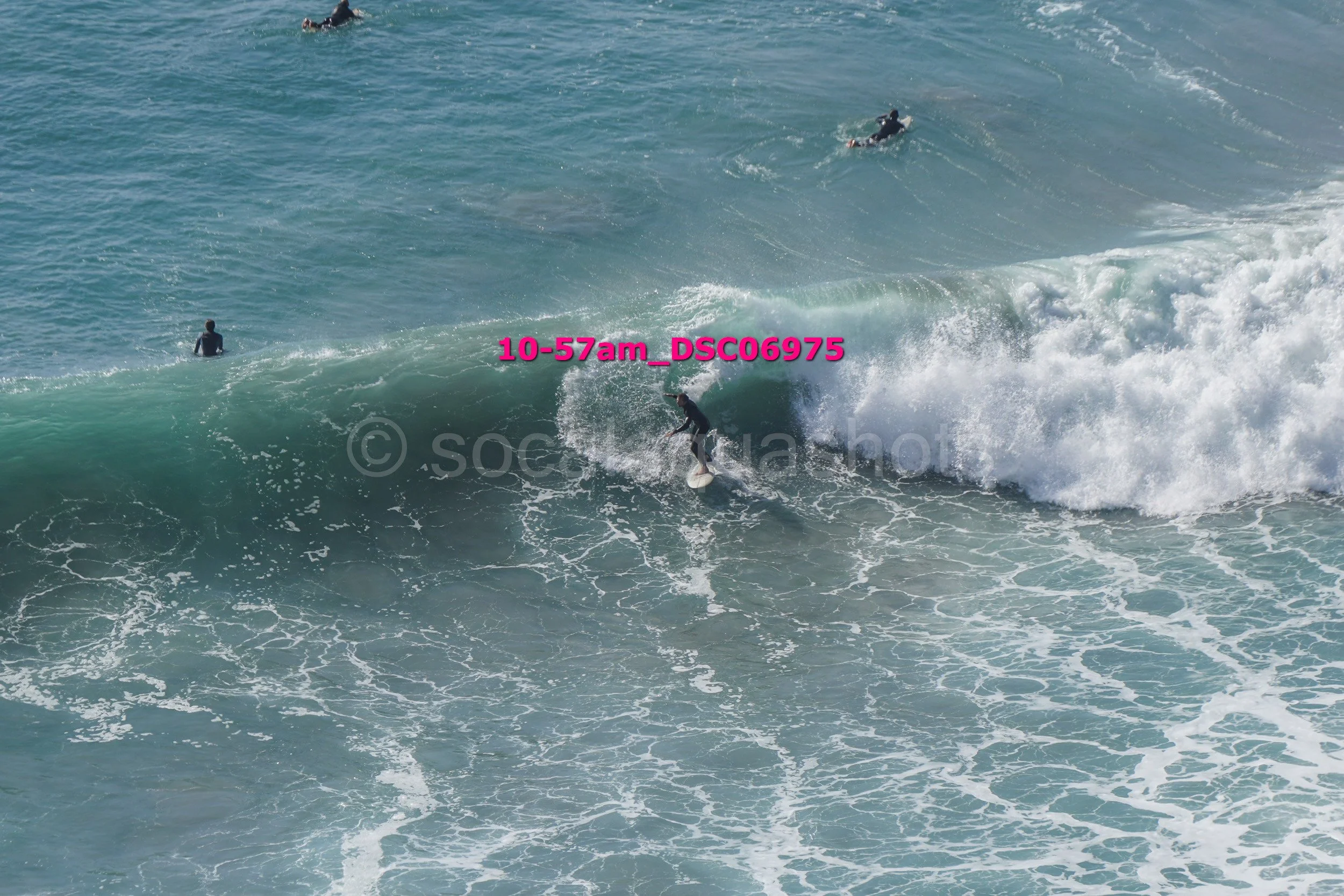 A surfer riding a wave with three other surfers in the water nearby.