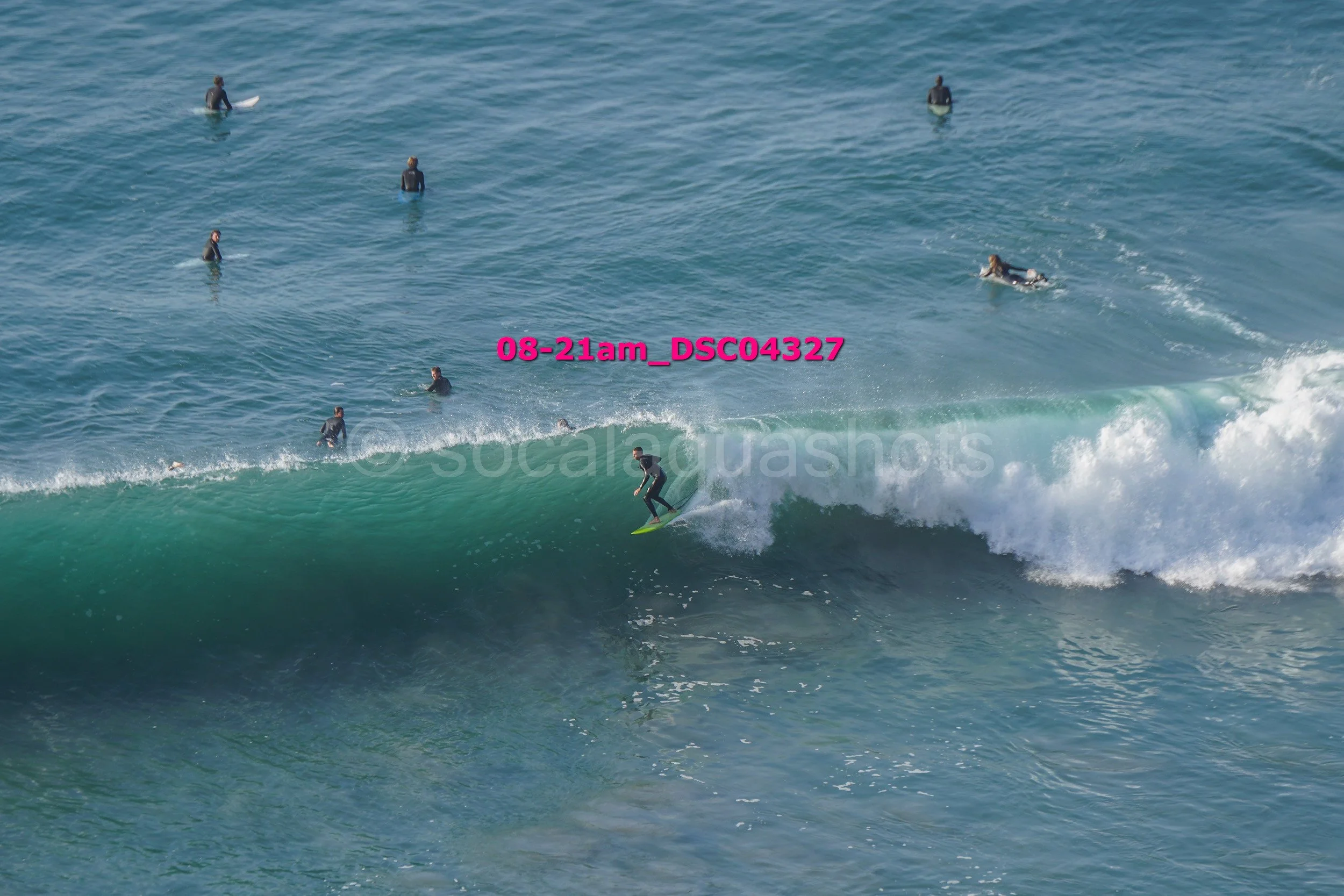 A person surfing on a wave with several people in the water watching.