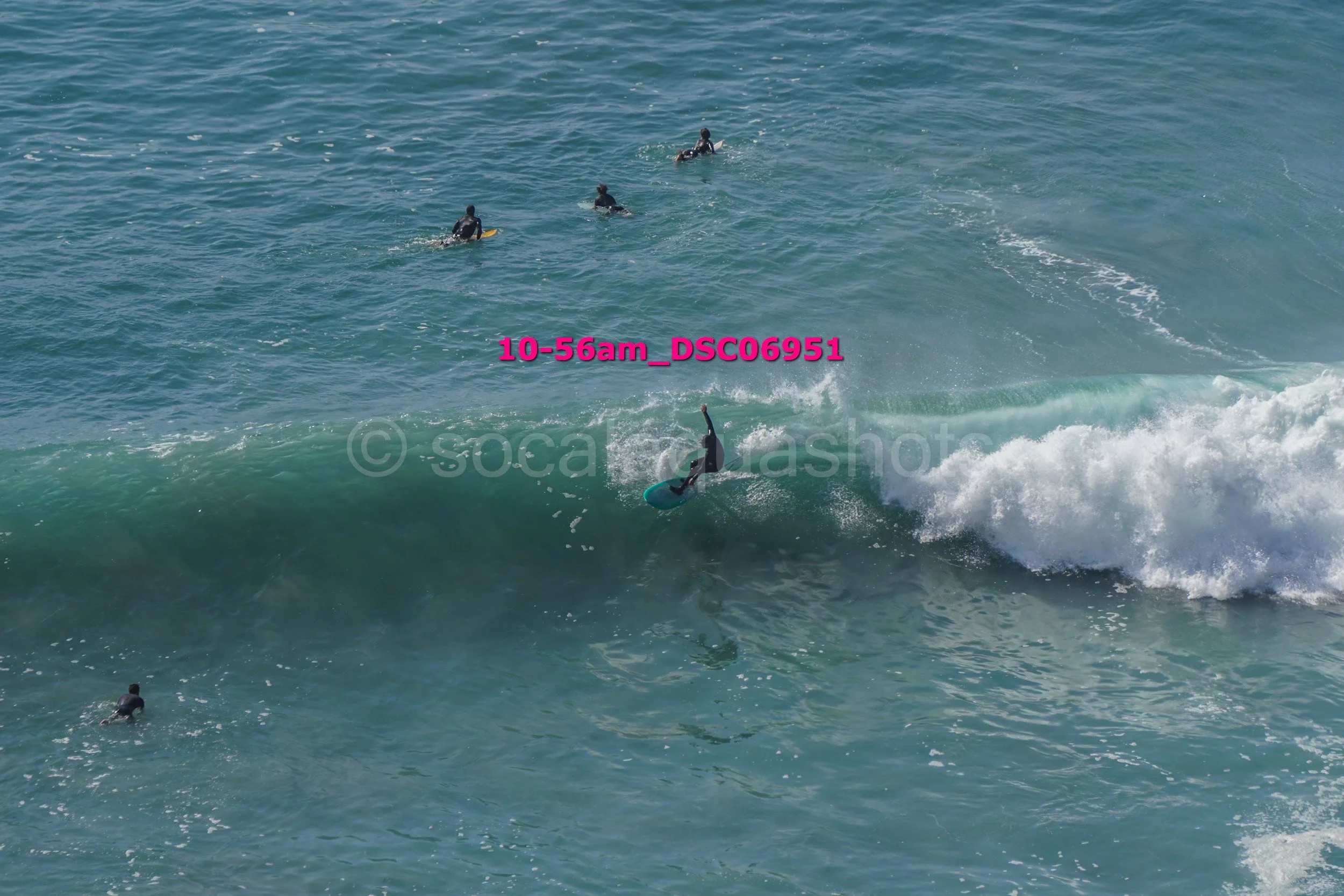 Surfer riding a wave in the ocean with a group of surfers in the background