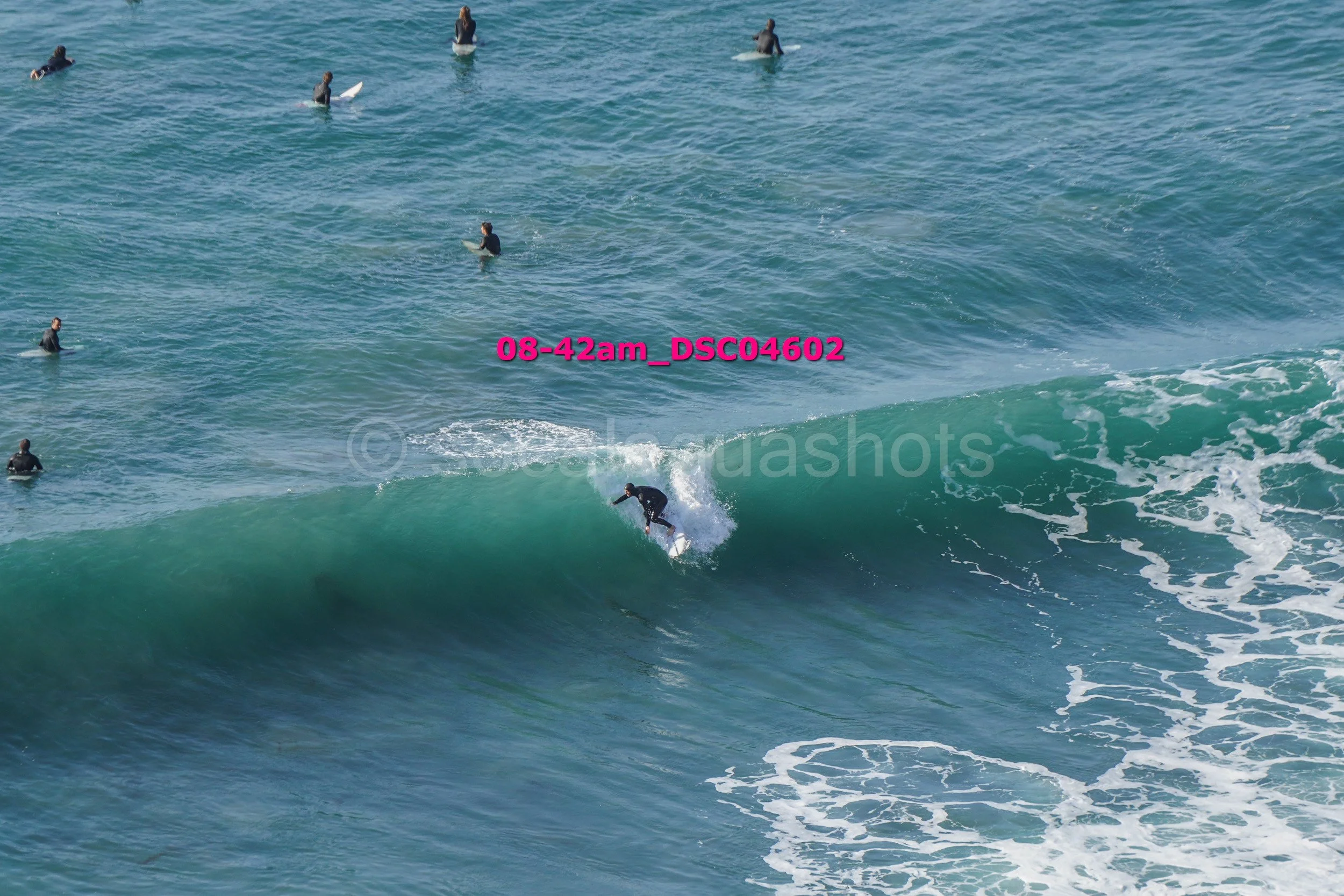 A surfer riding a wave with several surfers in the background in the ocean.