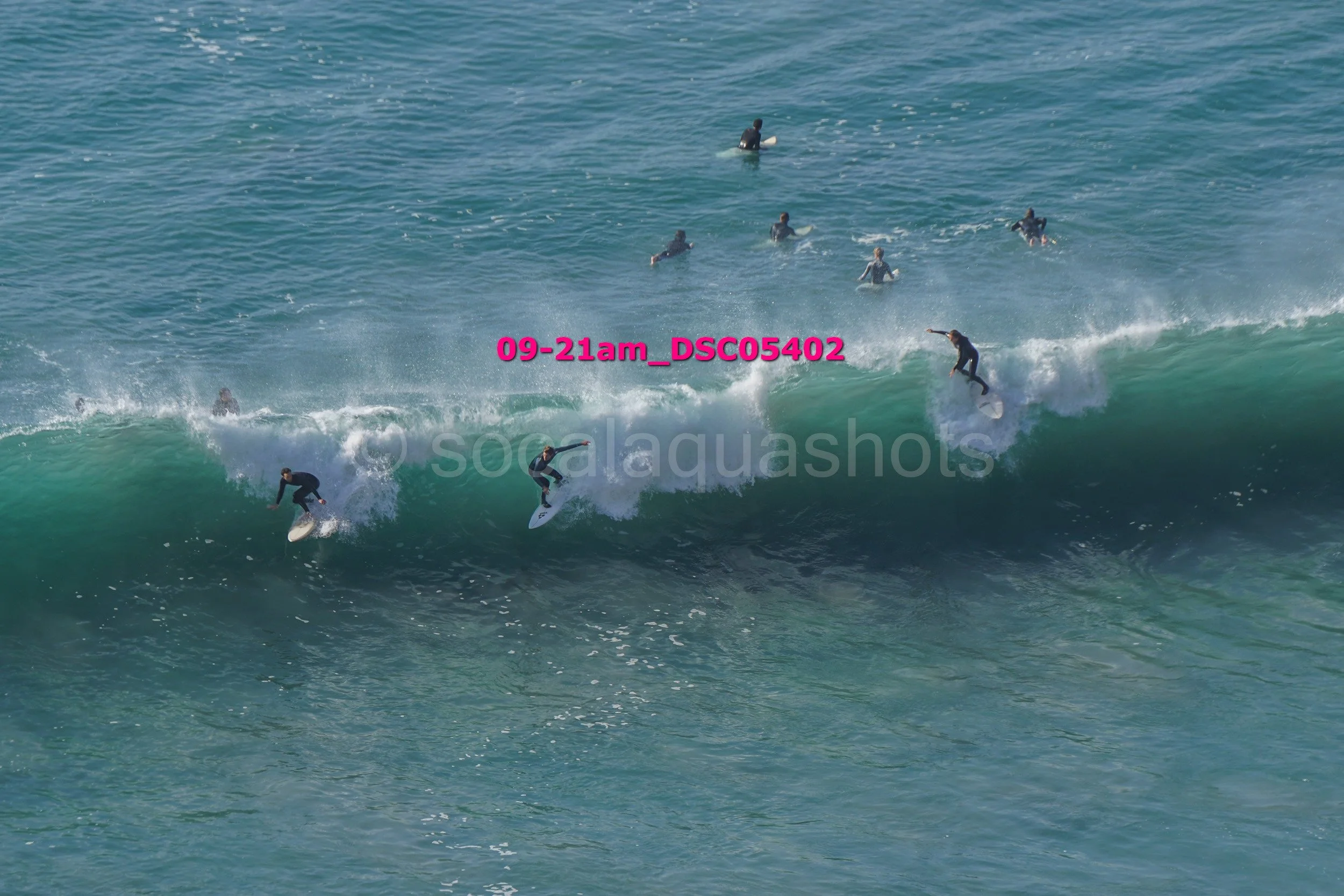 Multiple surfers riding and catching waves in the ocean during daytime.