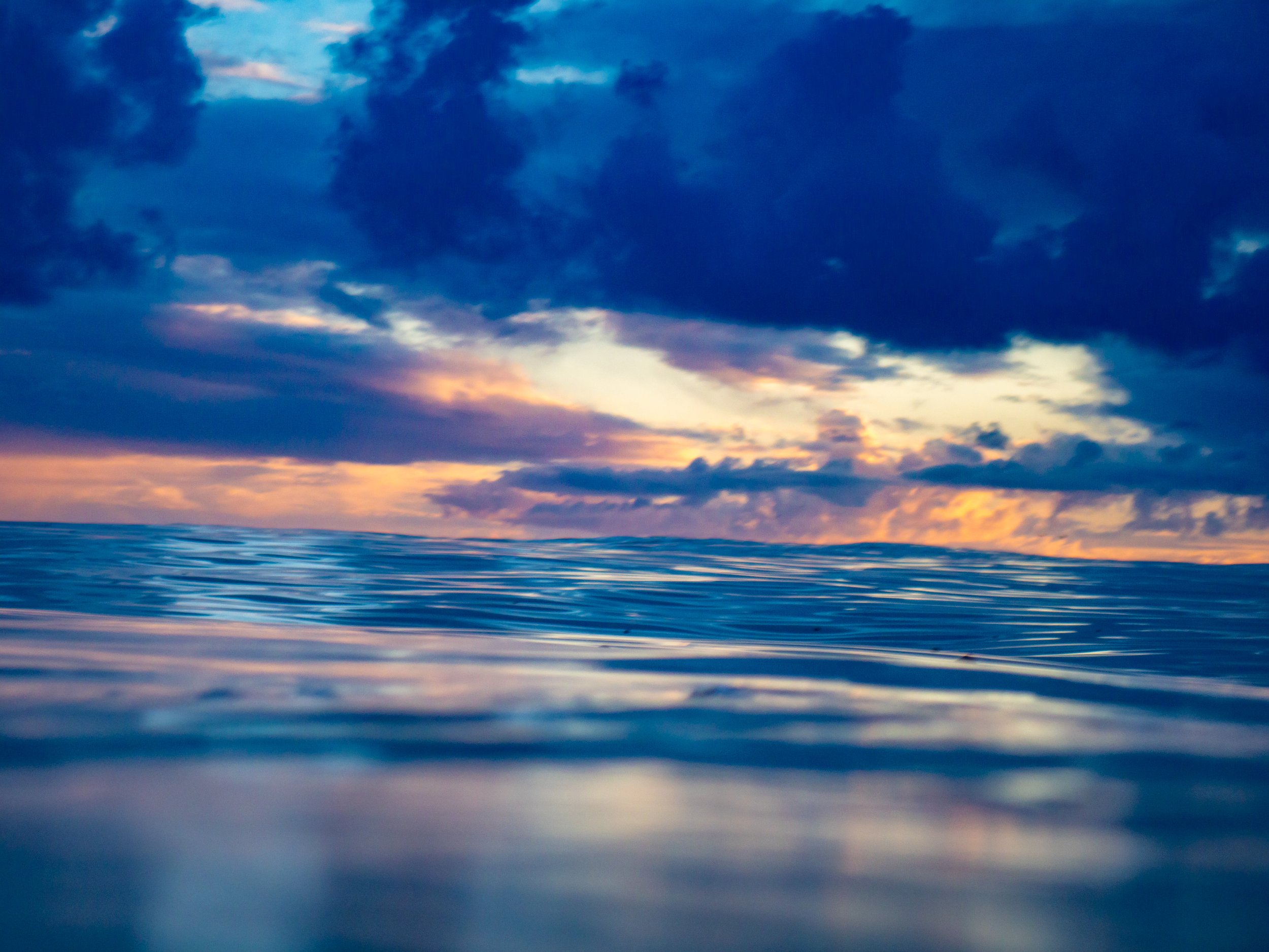 Calm ocean with a colorful sunset under a partly cloudy sky.