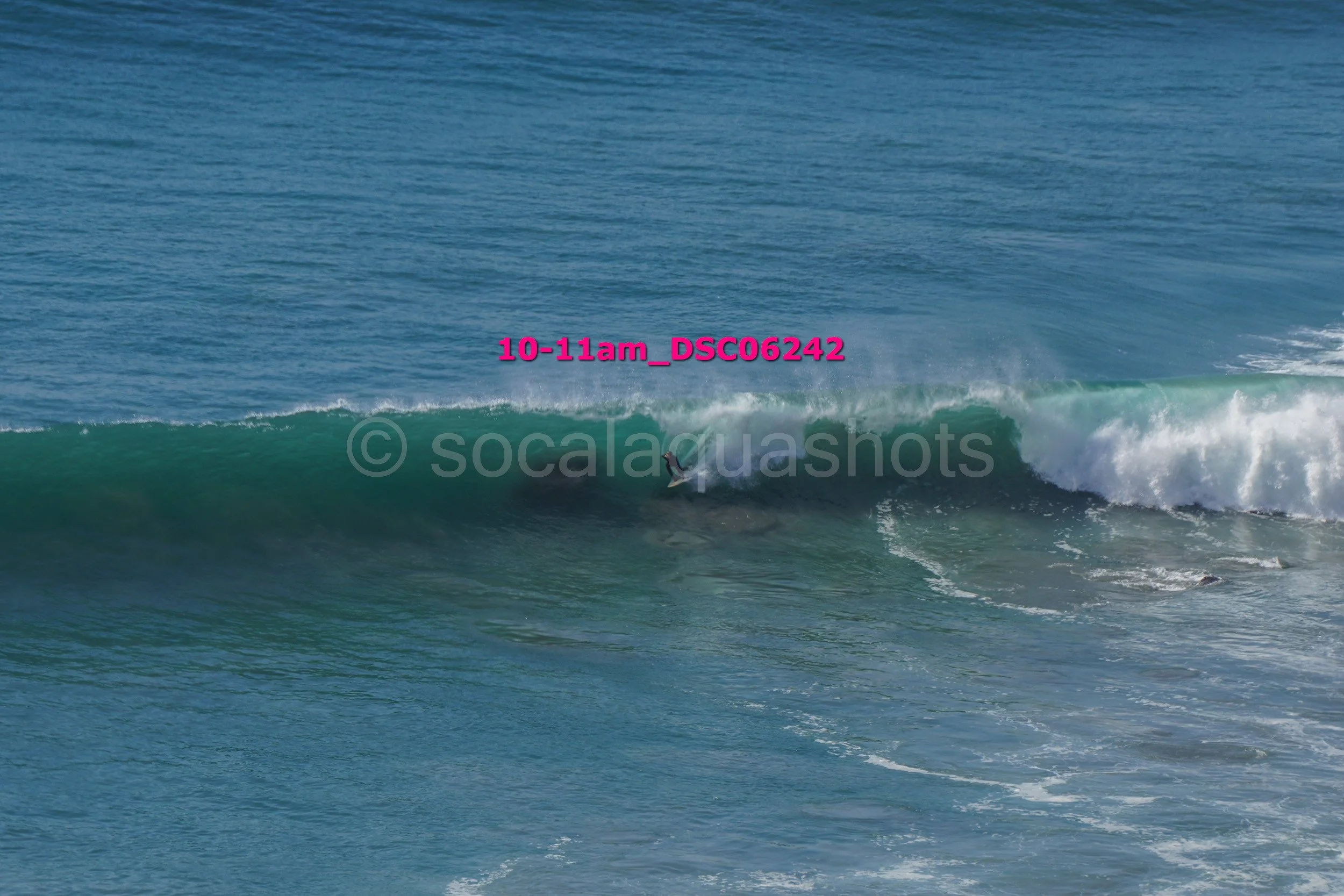 A surfer riding inside the barrel of a wave in the ocean during daylight.