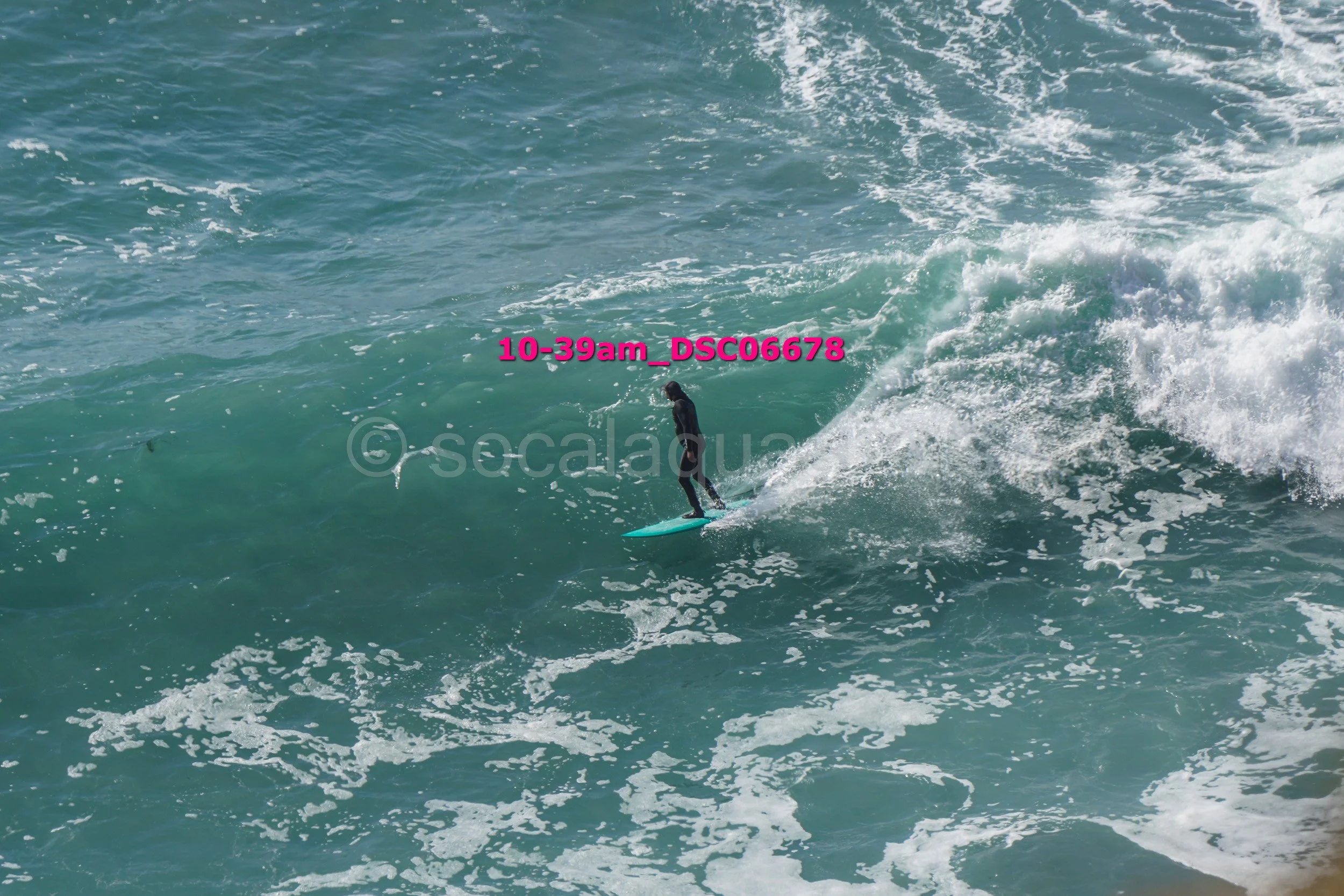 A person surfing on a large wave in the ocean, wearing a wetsuit.