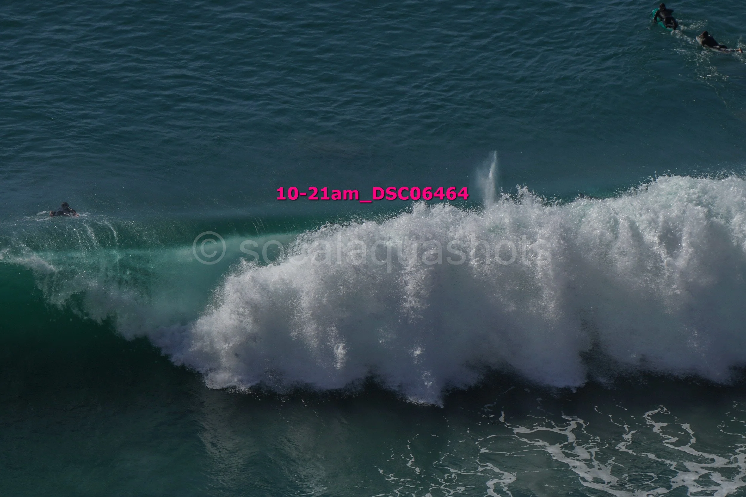 A group of surfers riding large waves in the ocean, with some submerged and others paddling on their boards.