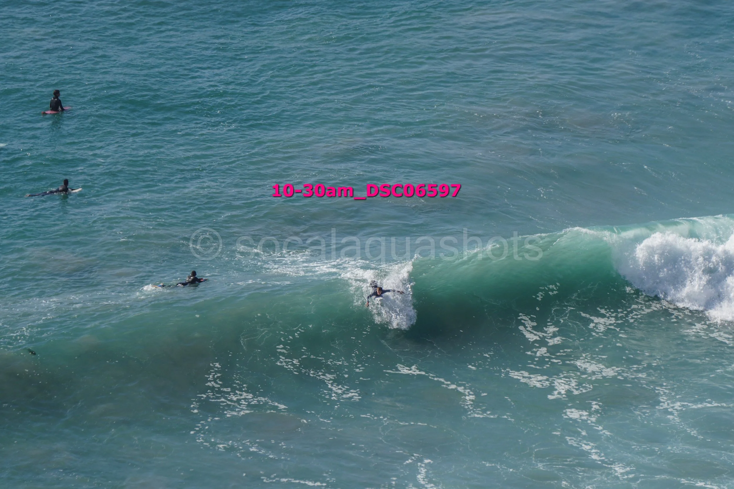 Surfer riding a wave while others wait in the water at the beach.