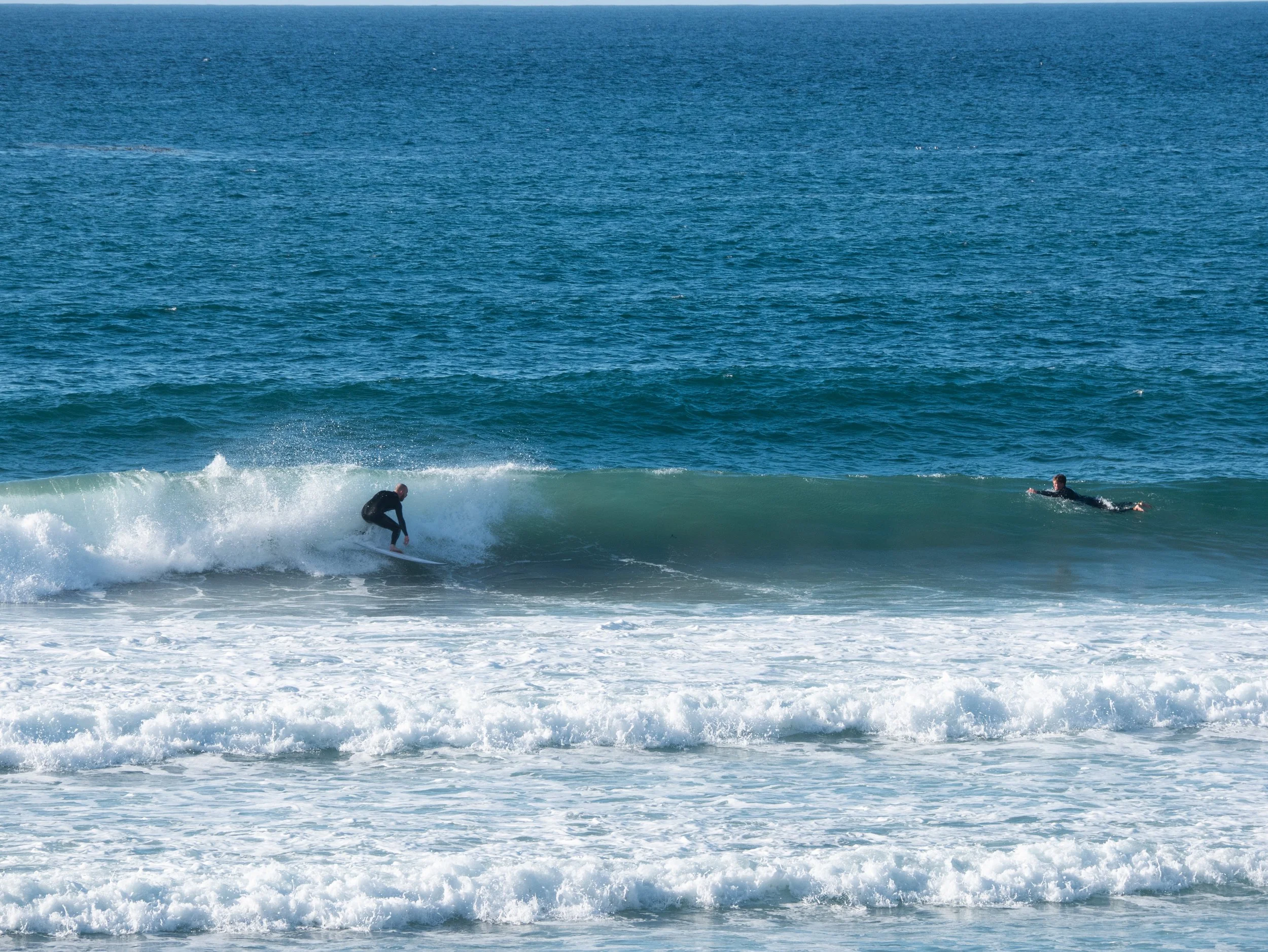 Two people surfing on the ocean waves.