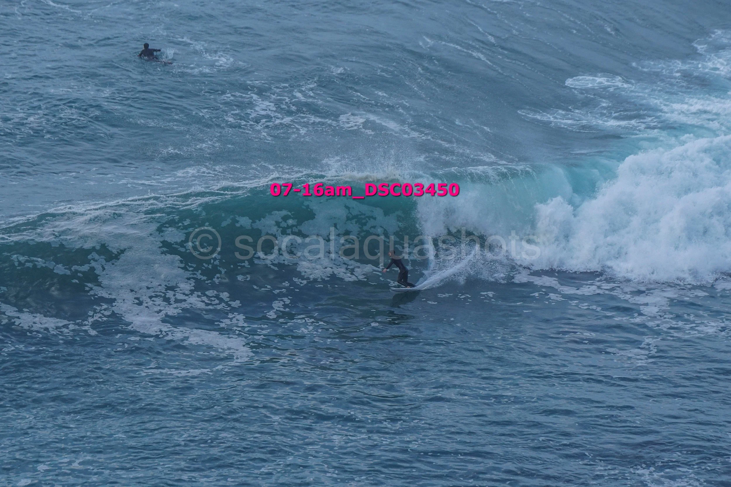 Surfer riding a wave with another person in the water in the background.