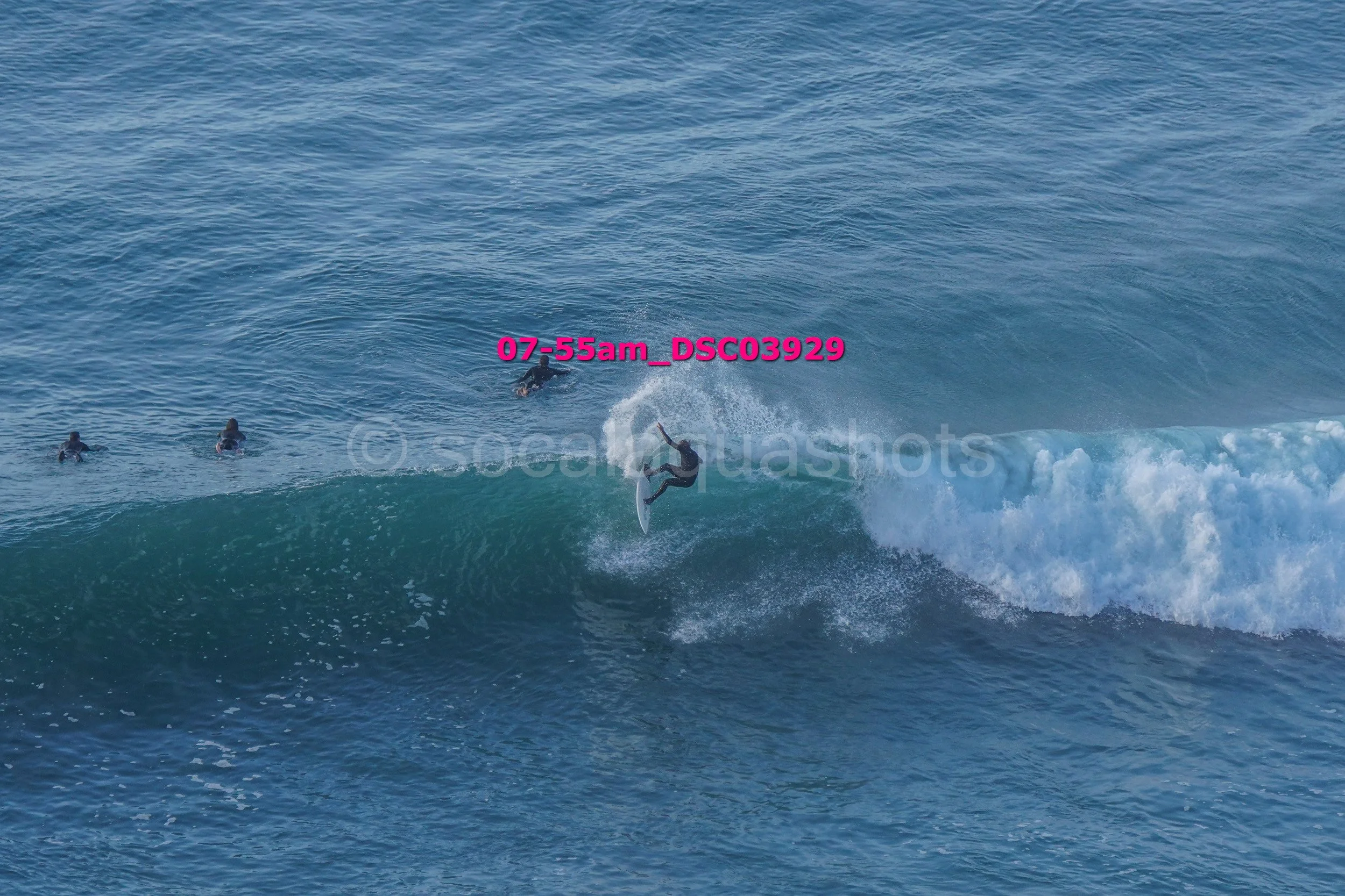Surfer riding a wave with three people watching from the water.