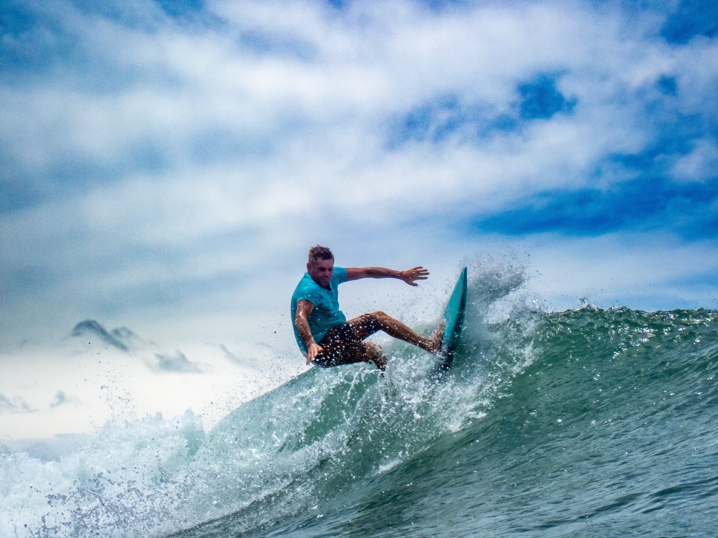 A man surfing on a wave in the ocean during daytime.