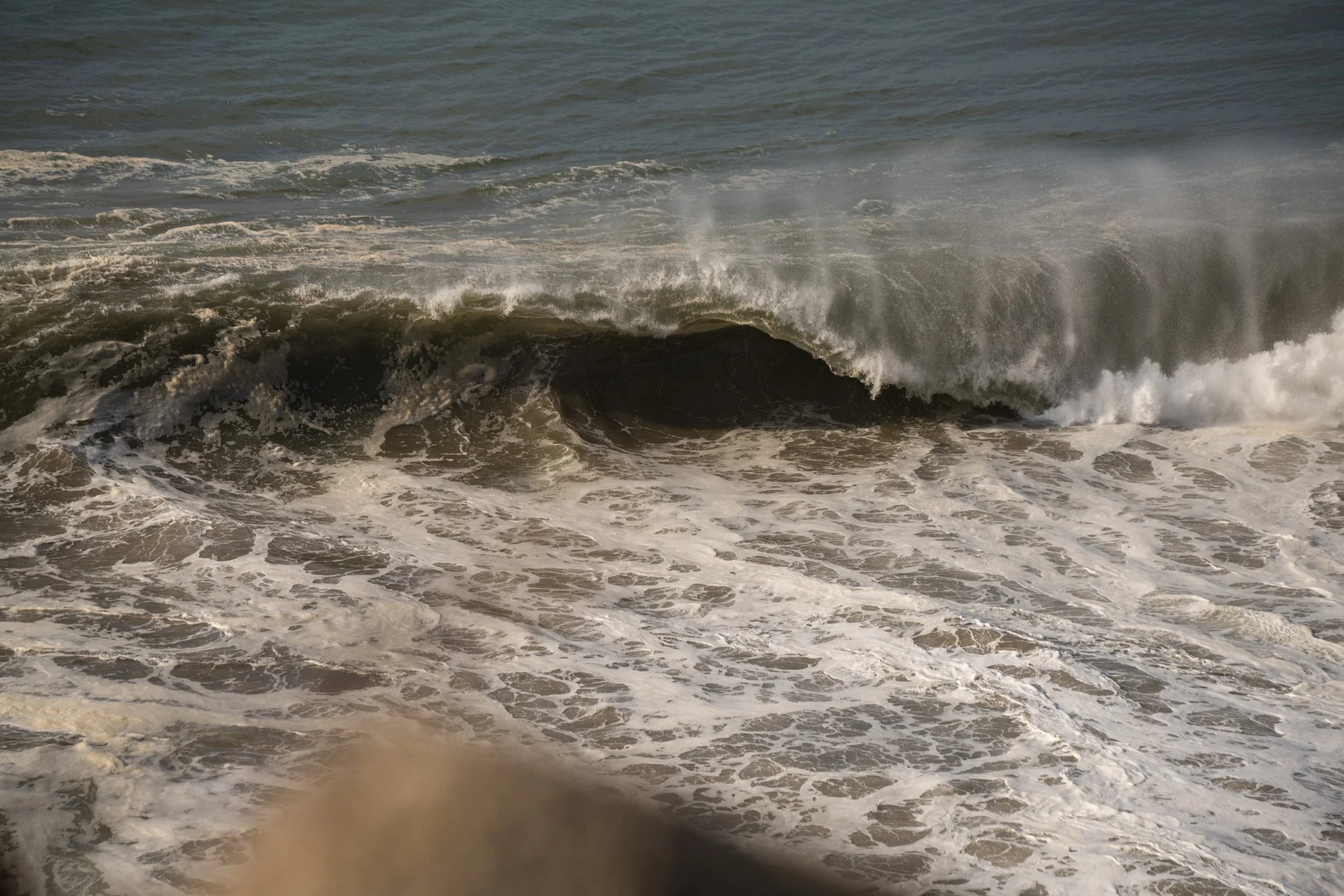 Ocean waves crashing onto the shoreline with foam and spray visible.