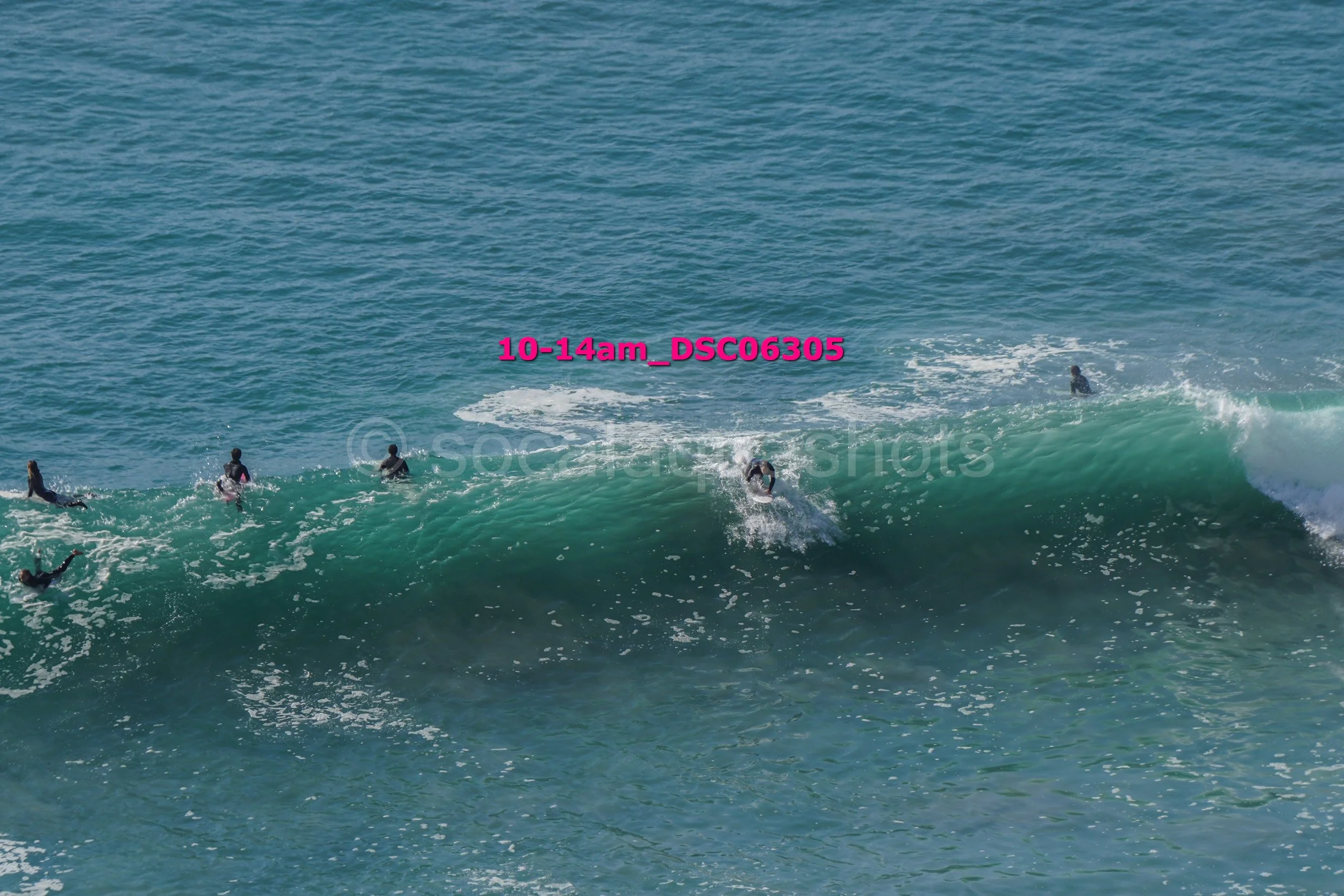 A group of people surfing on a wave in the ocean.