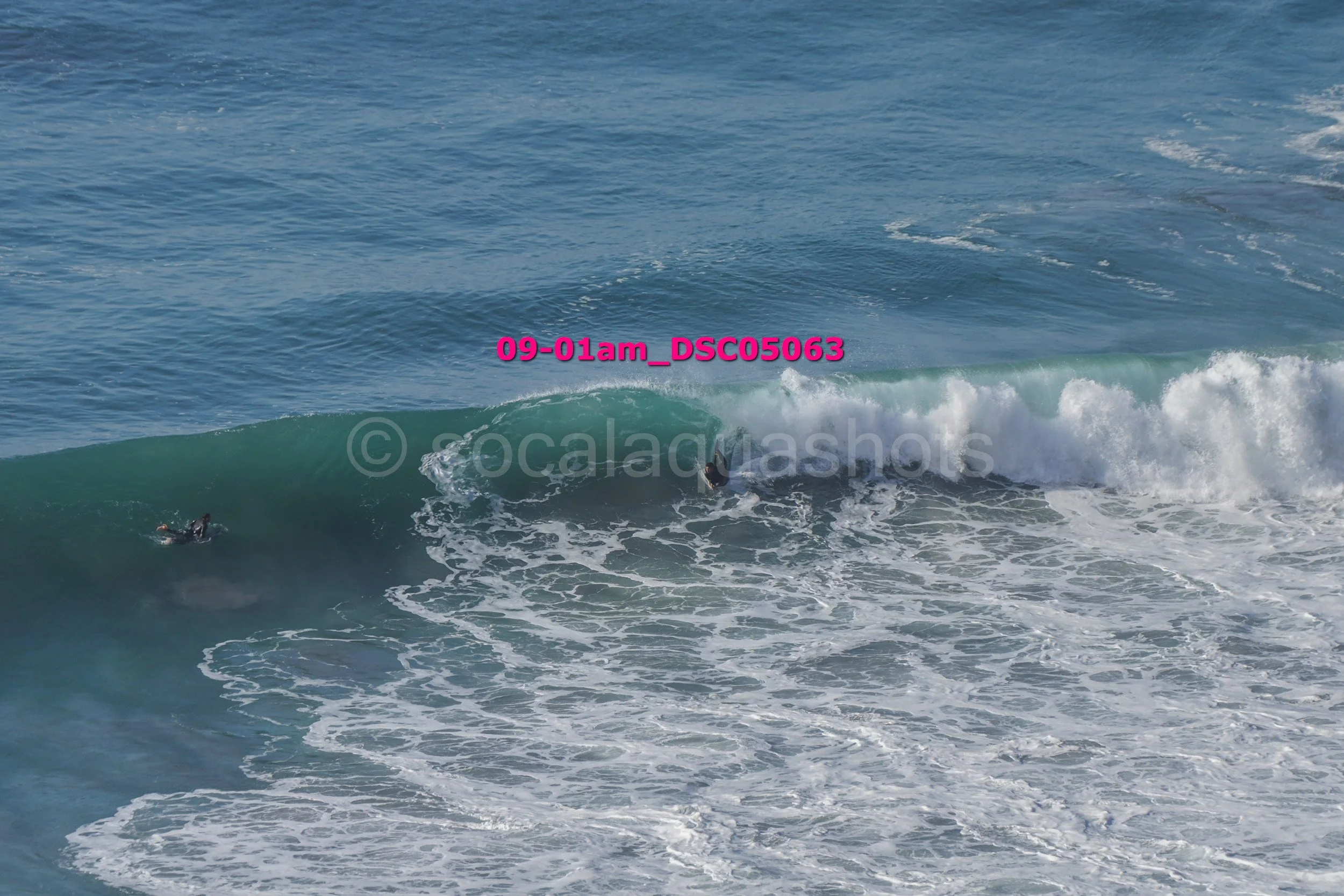 Surfers riding a large ocean wave.