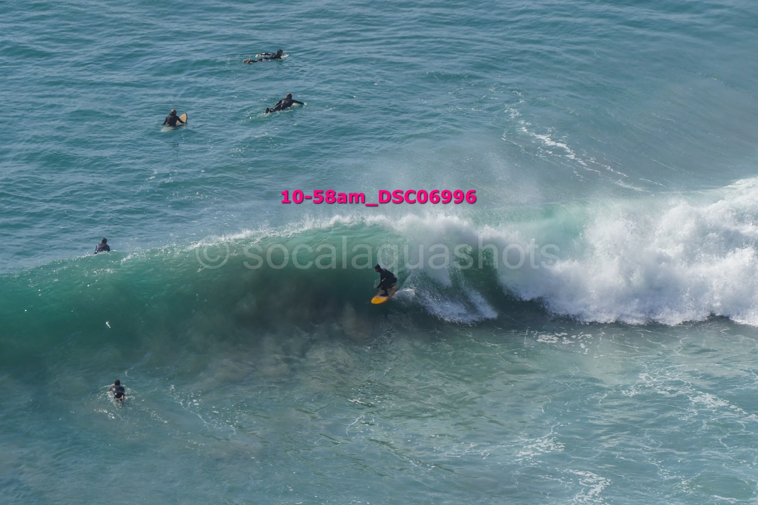 Surfer riding a wave with several people in the water watching.