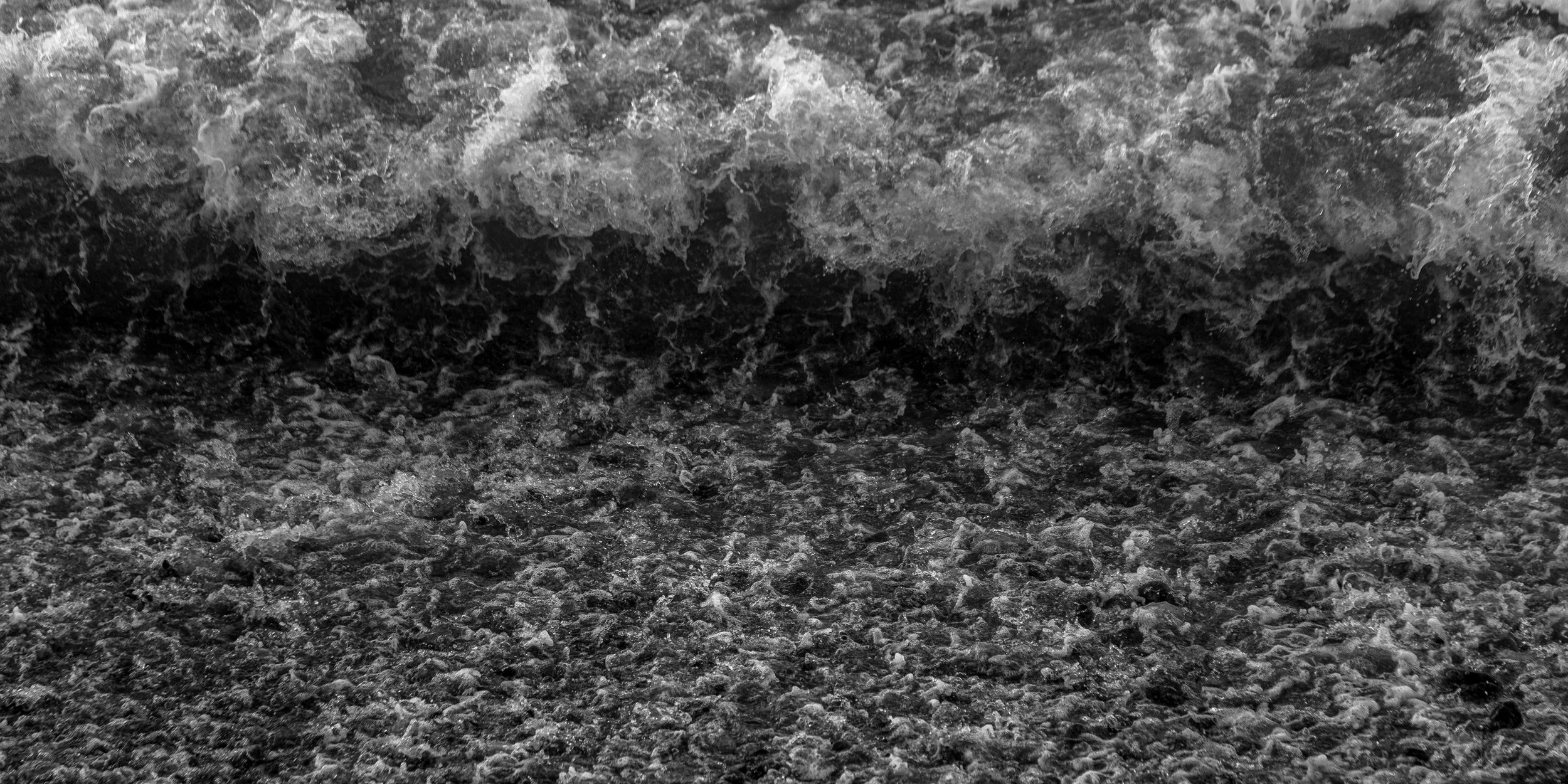 Black and white photo of ocean waves crashing onto the shore.