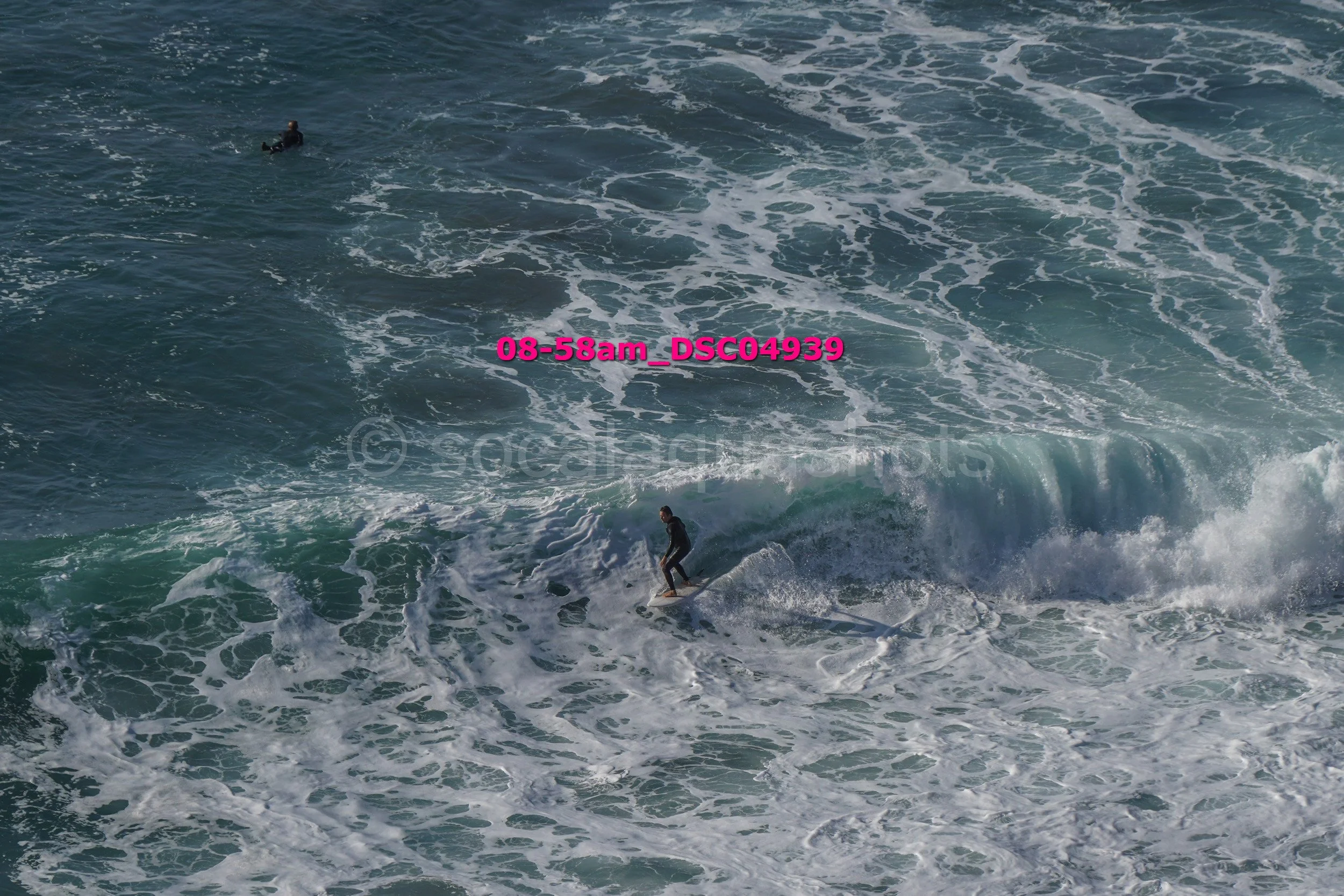 Surfer riding a wave in the ocean with another person in the water in the background.