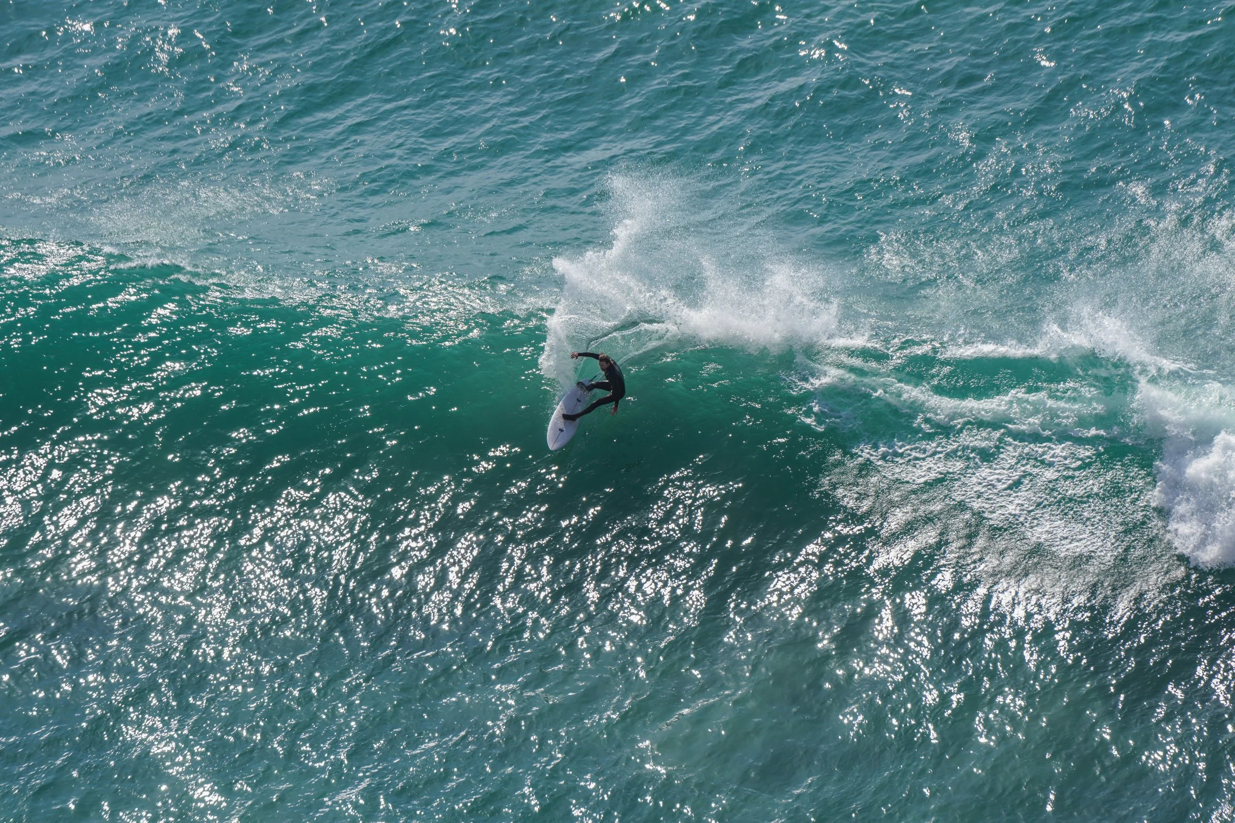 Surfer riding a wave in the ocean on a sunny day.