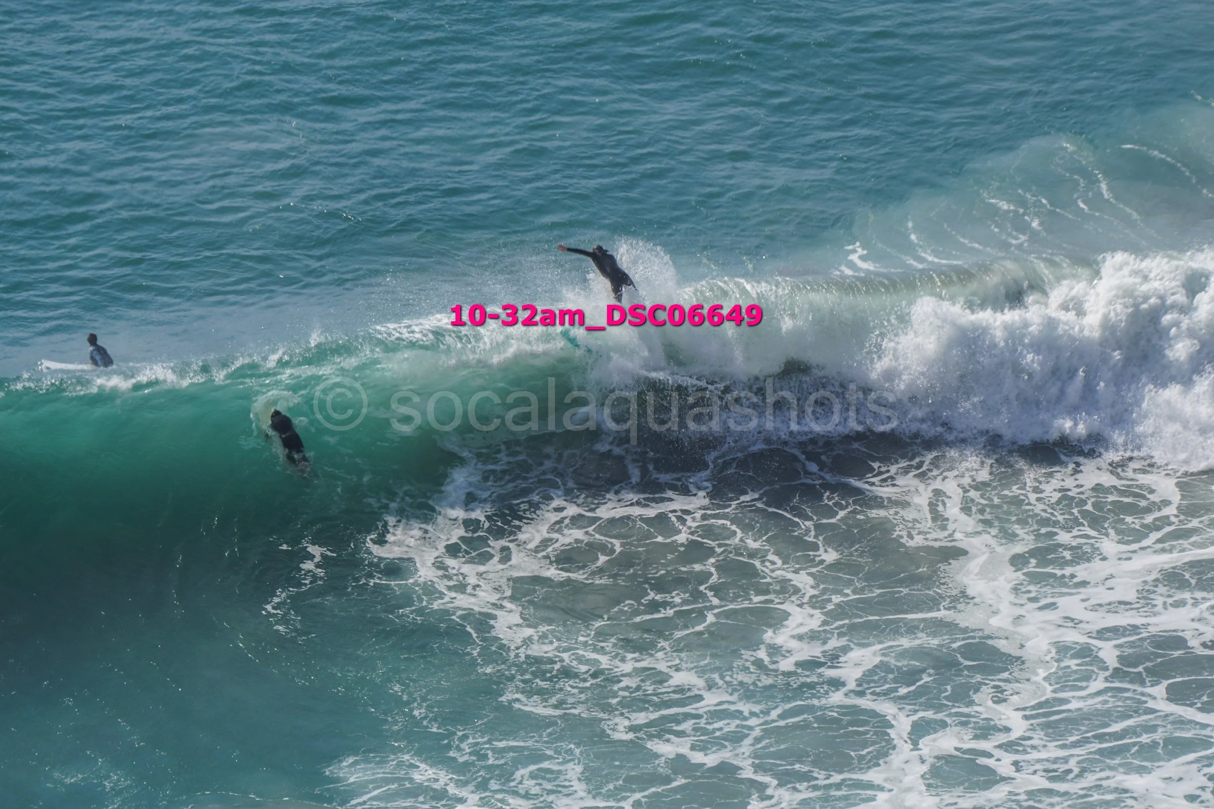 Surfers riding large ocean waves with foam and spray.