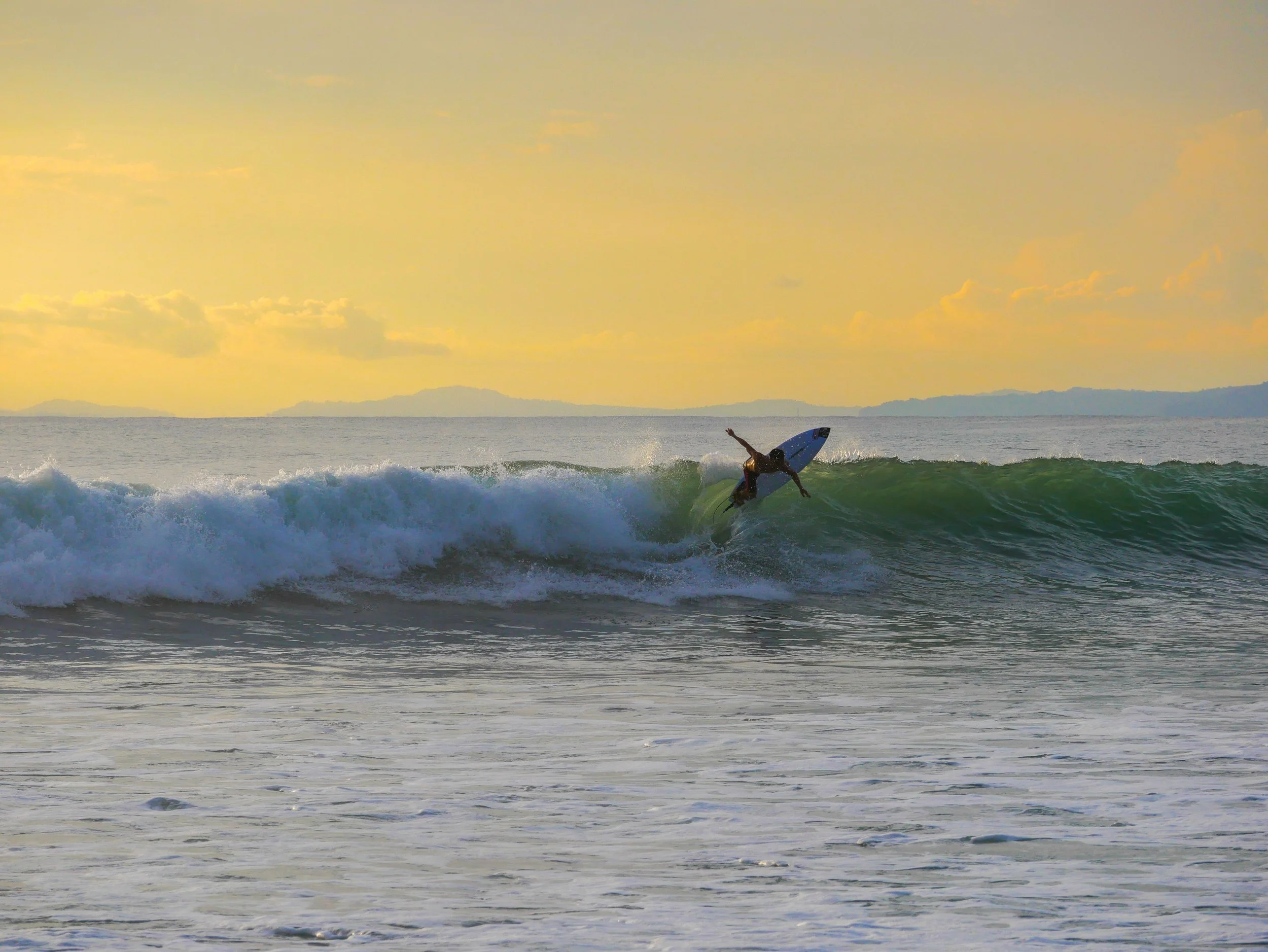 Person surfing on a wave at sunset