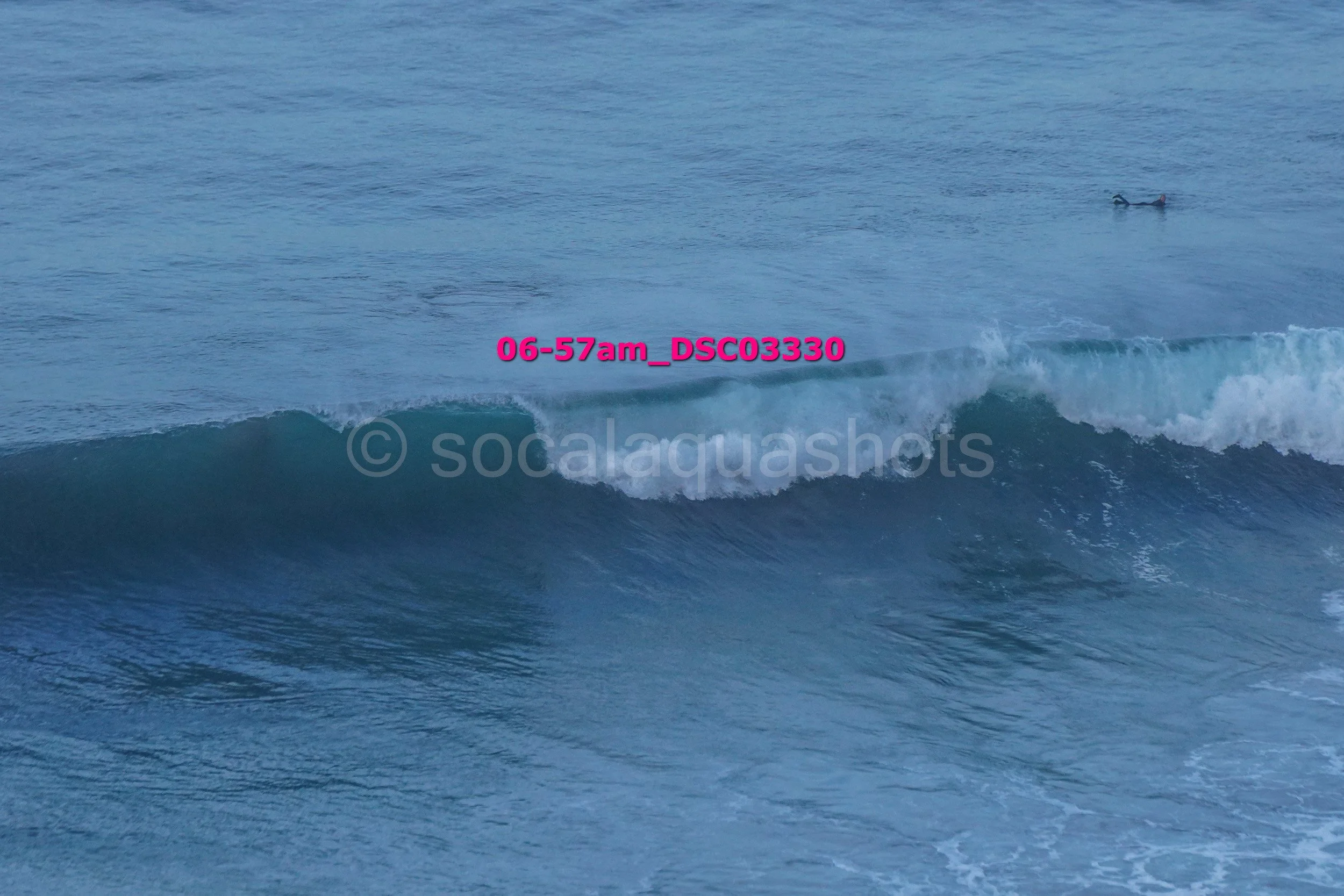 Waves in the ocean with a surfer in the distance.