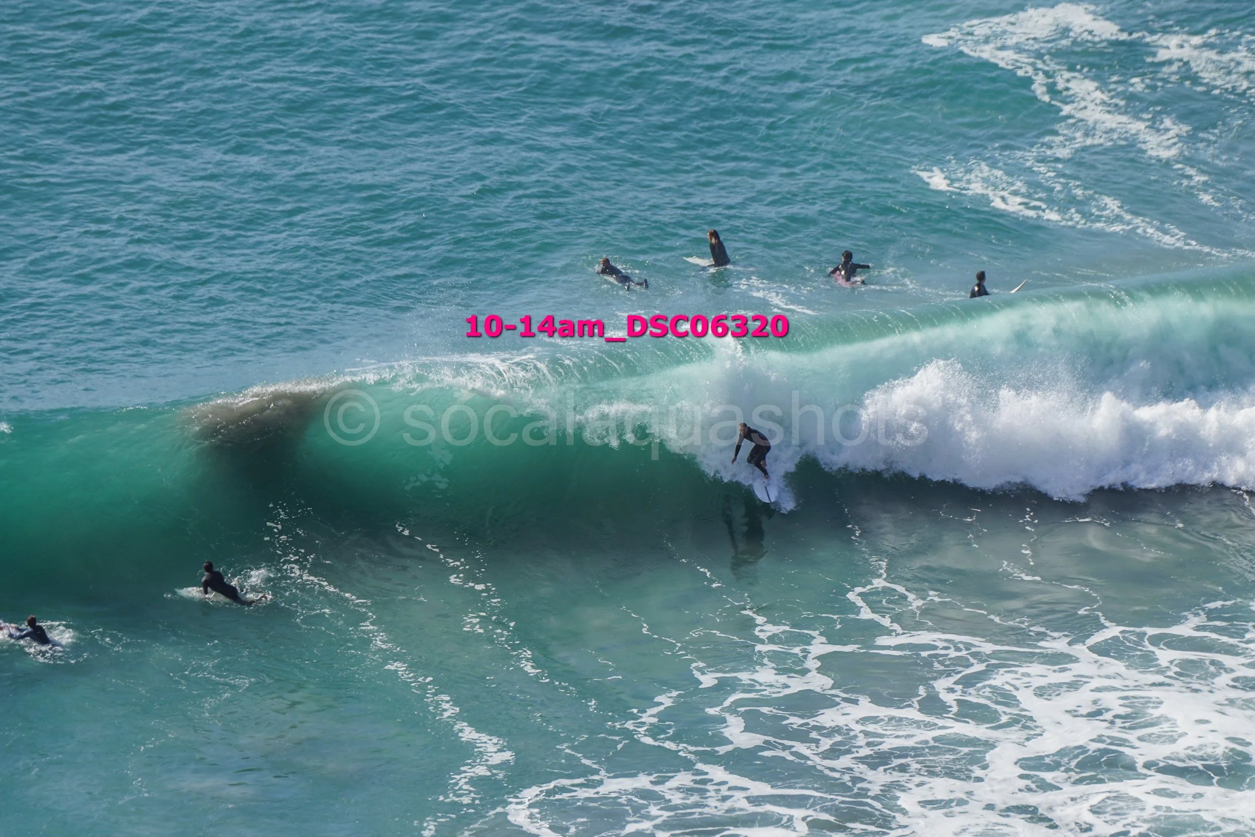 Surfers riding and waiting on ocean waves with other surfers in the background