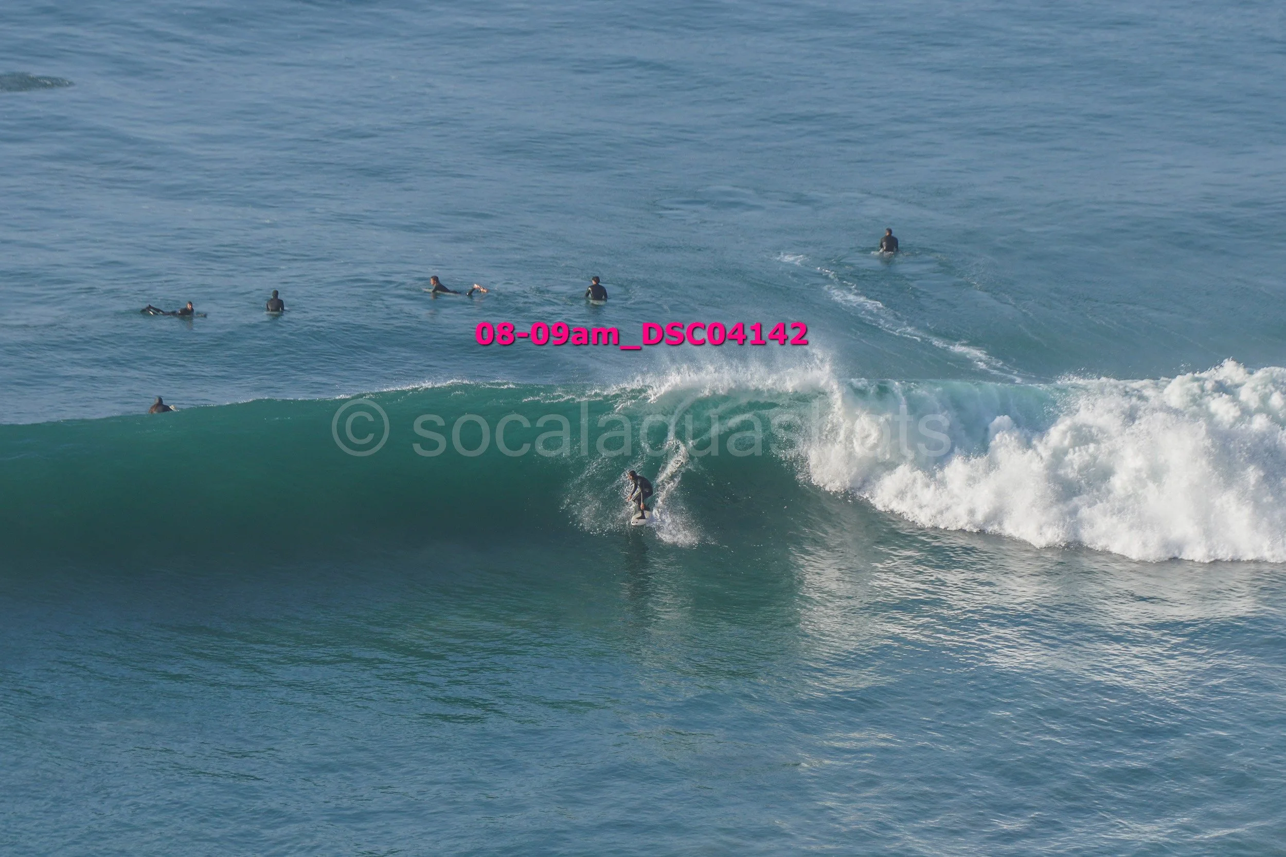 Surfer riding a wave with several surfers in the water in the background near the shoreline.