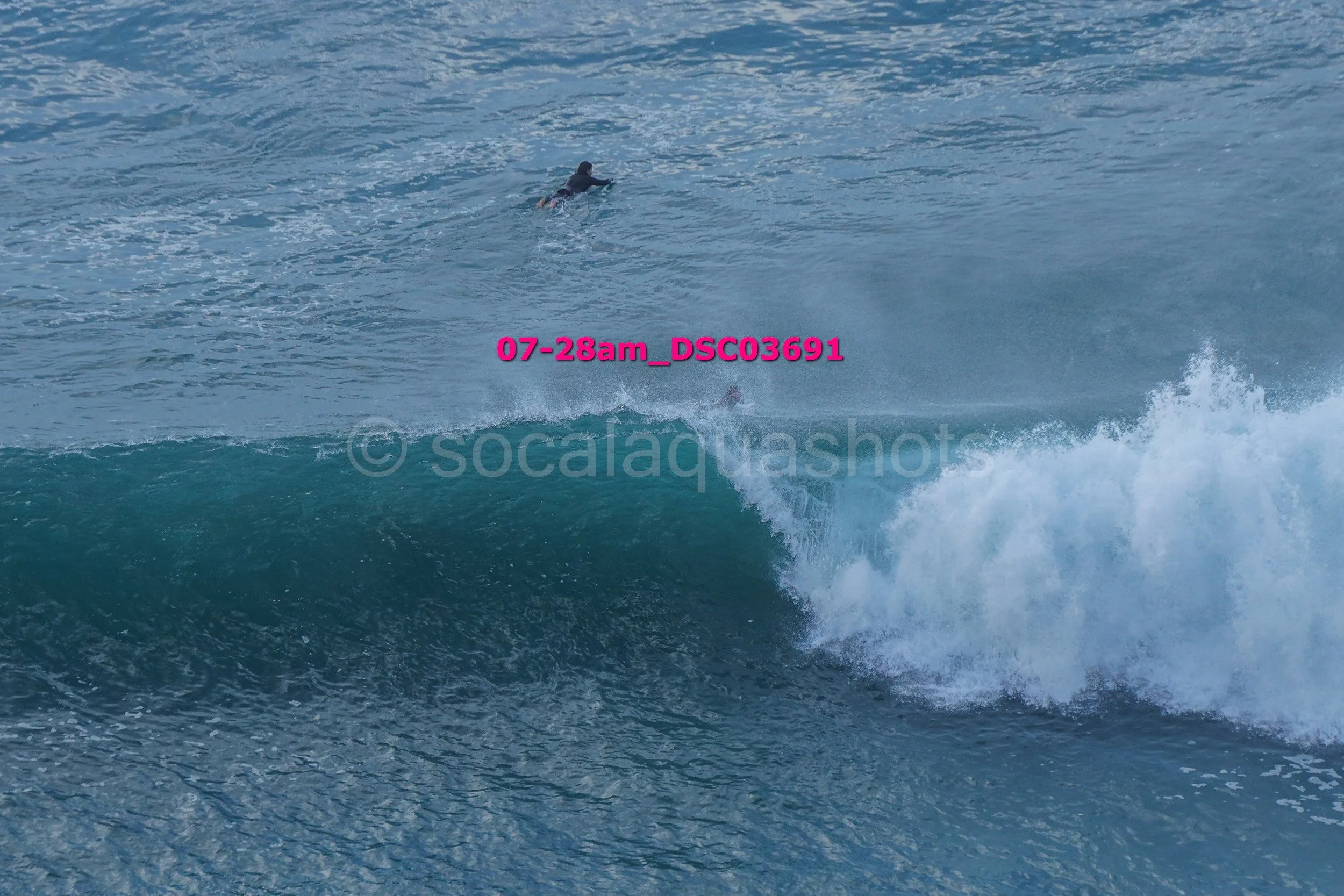 A person swimming in the ocean near a breaking wave.
