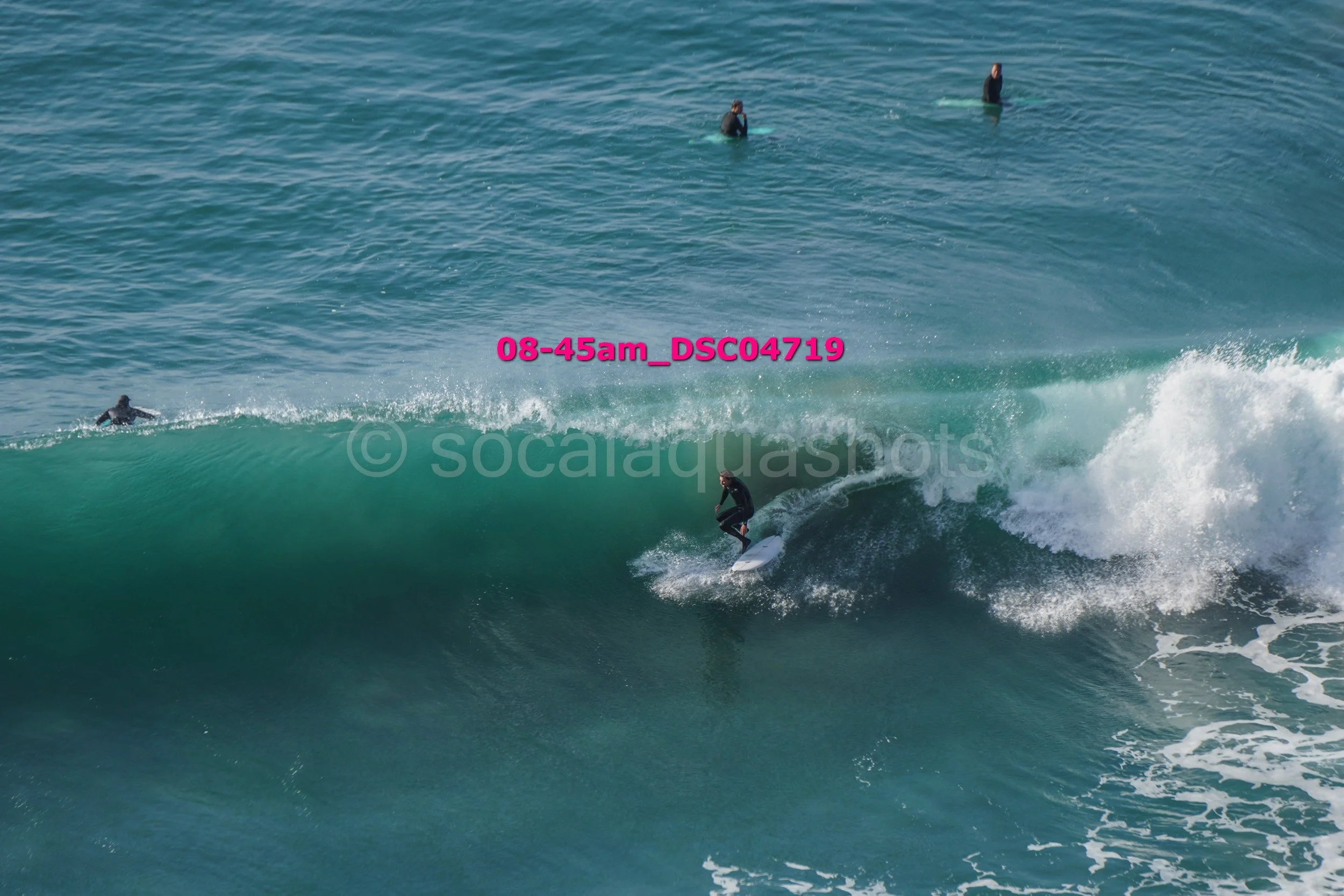 A person surfing on a wave near the shoreline with other surfers in the distance in the ocean.