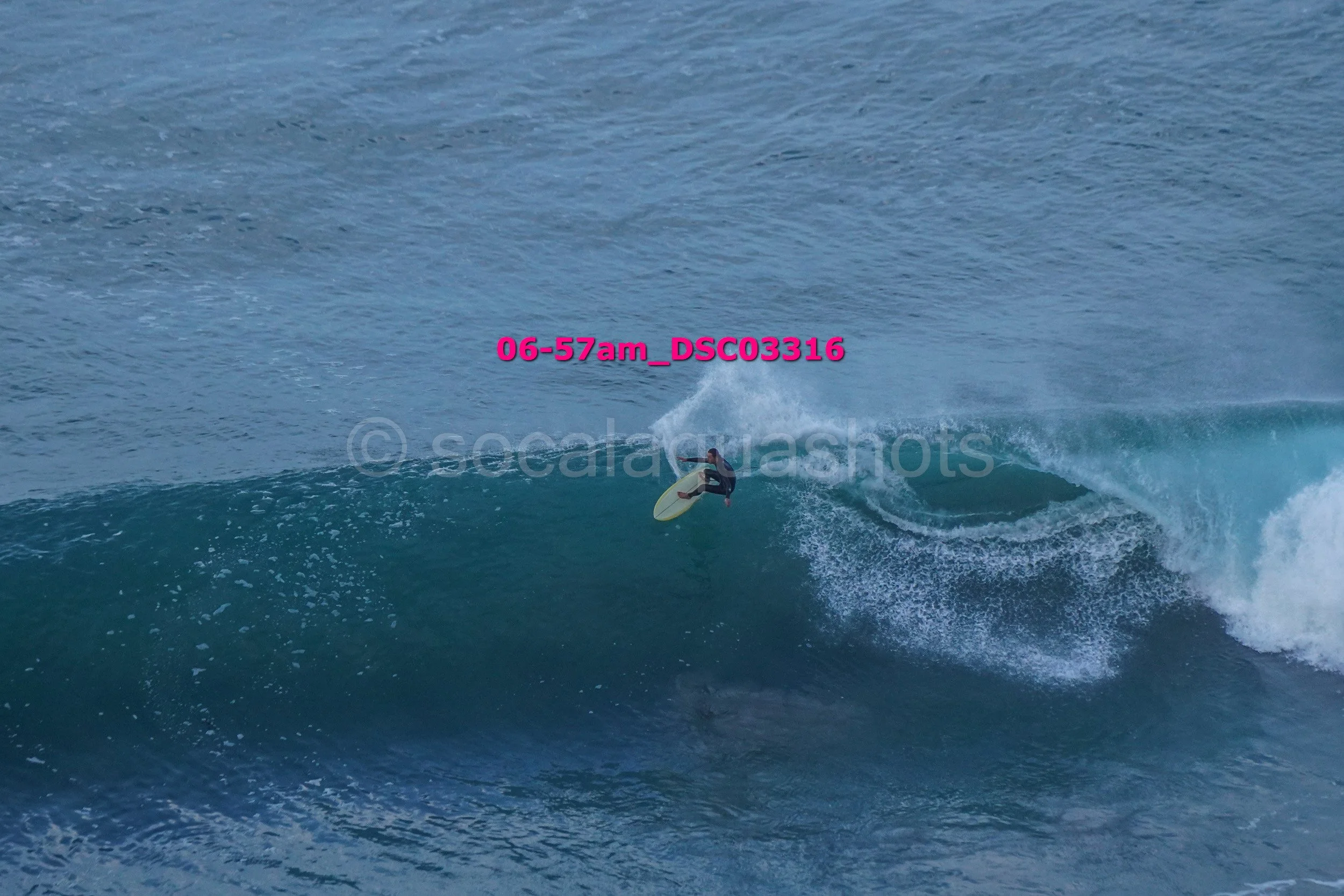 A surfer riding a wave in the ocean, with water splashing around him and a water spray behind him.