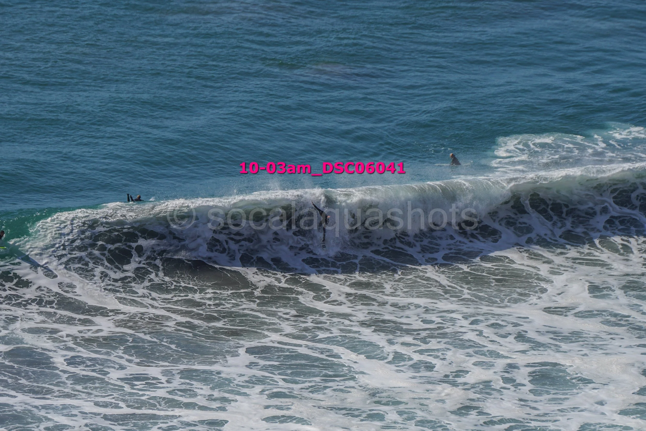 Surfers riding and falling off large ocean waves at the beach.
