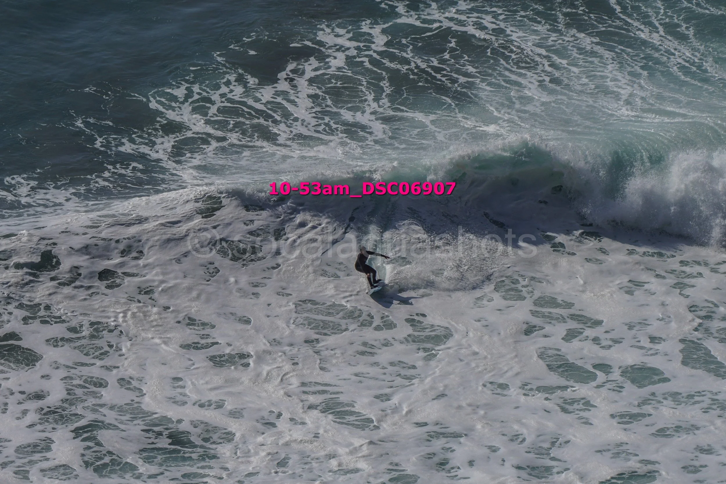 A person surfing on a wave in the ocean, with water foaming around them.
