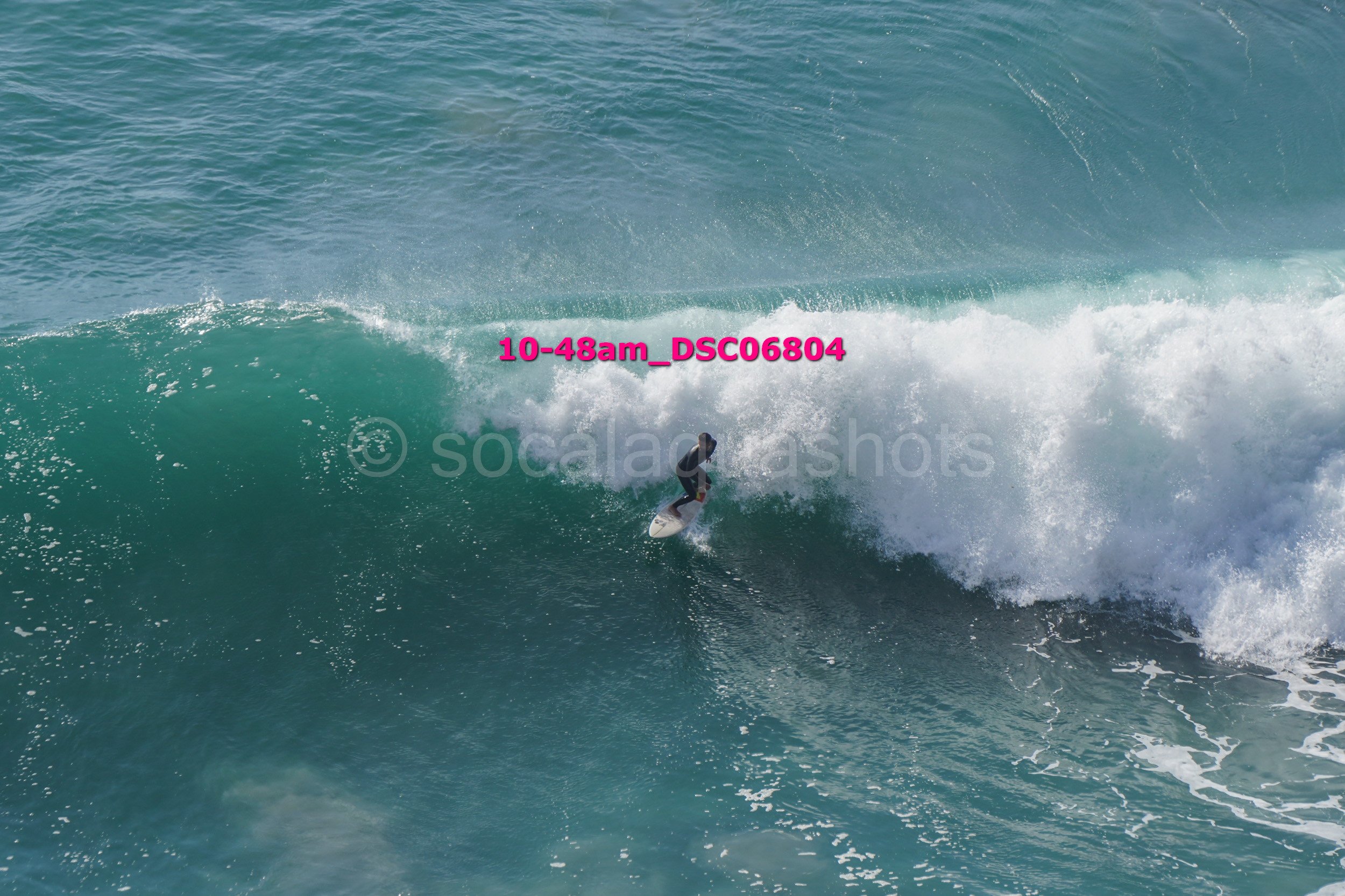 A person surfing on a large ocean wave with foam and water spray.