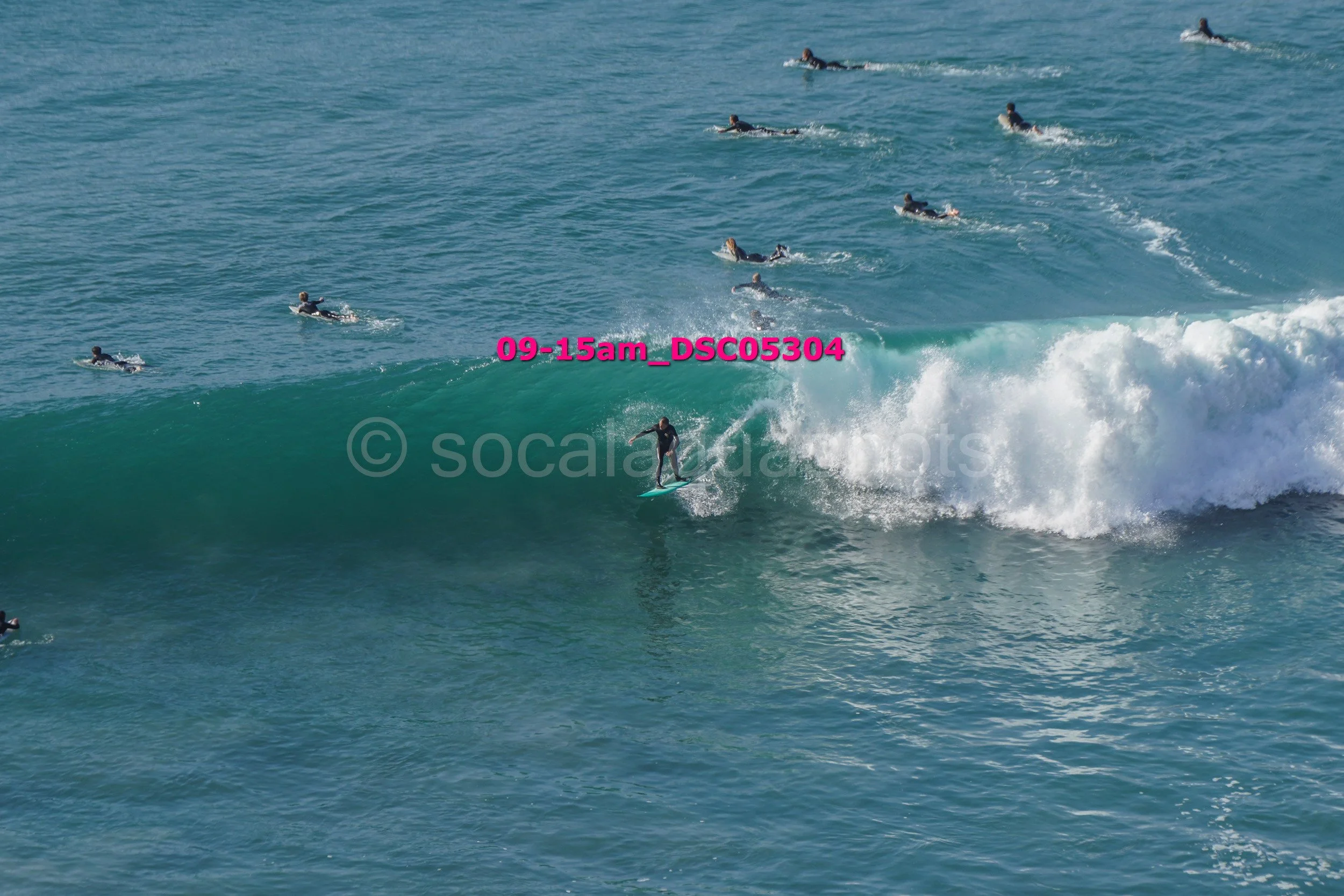 Surfer riding a wave with multiple surfers in the background in the ocean.