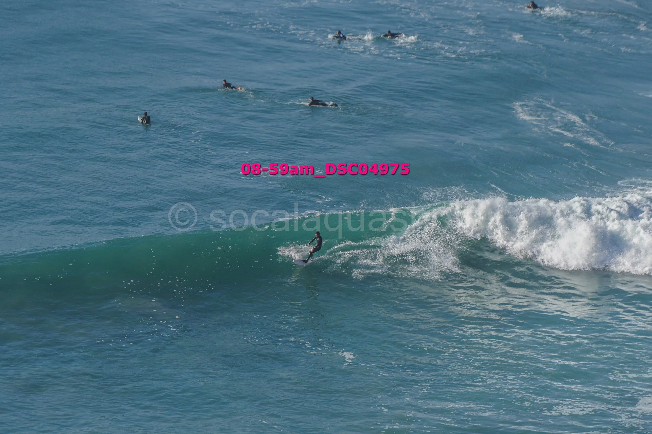 Surfer riding a wave with several surfers in the water nearby.