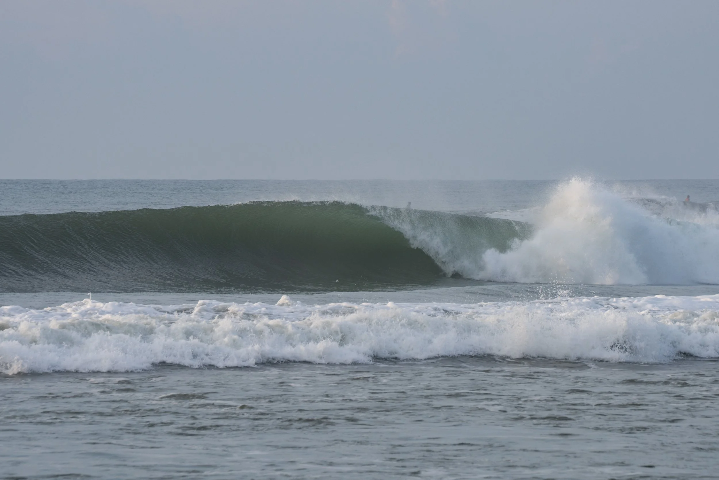 Ocean waves with a surfer riding a wave in the distance.