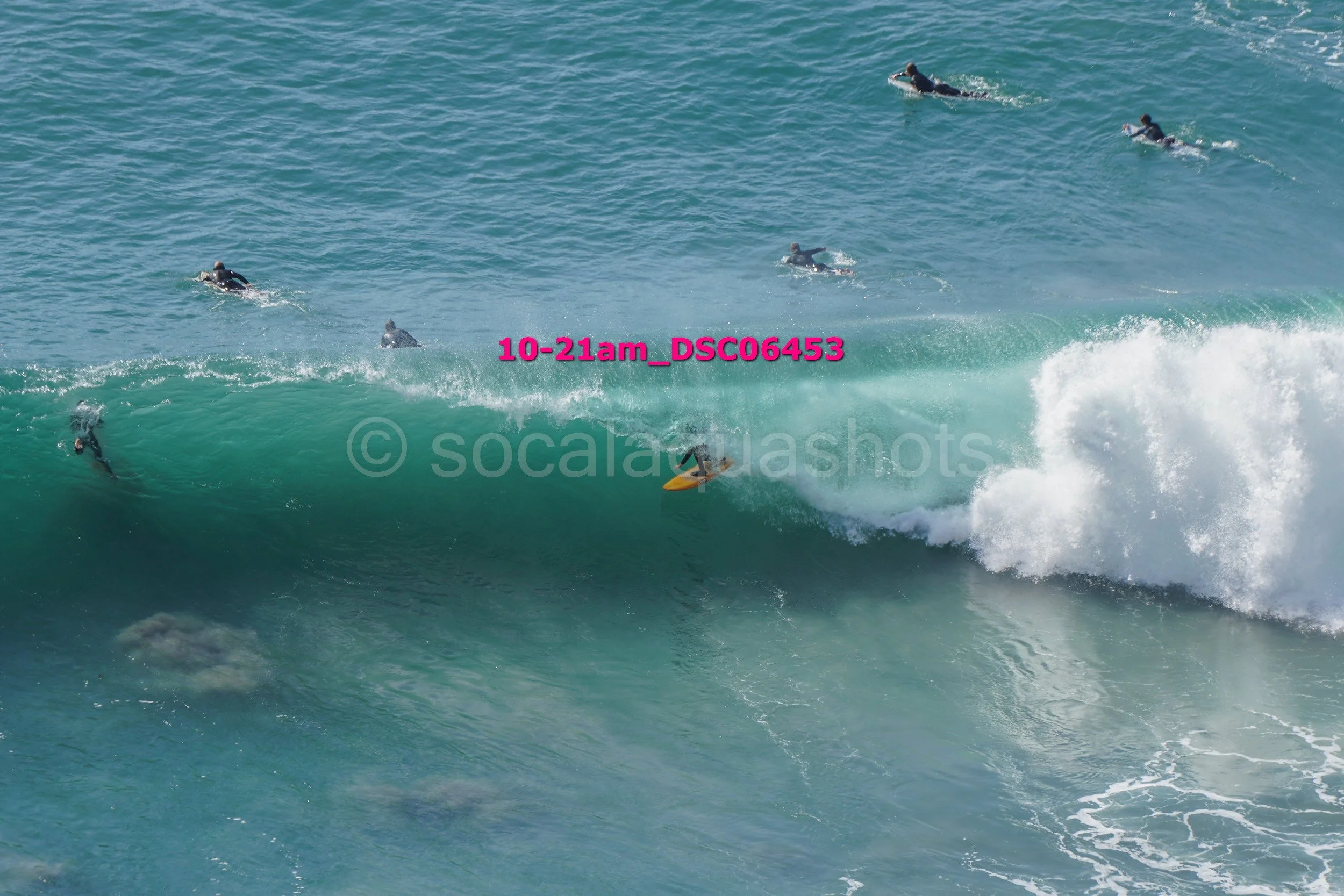 Surfer riding a wave with several surfers in the water in the background.