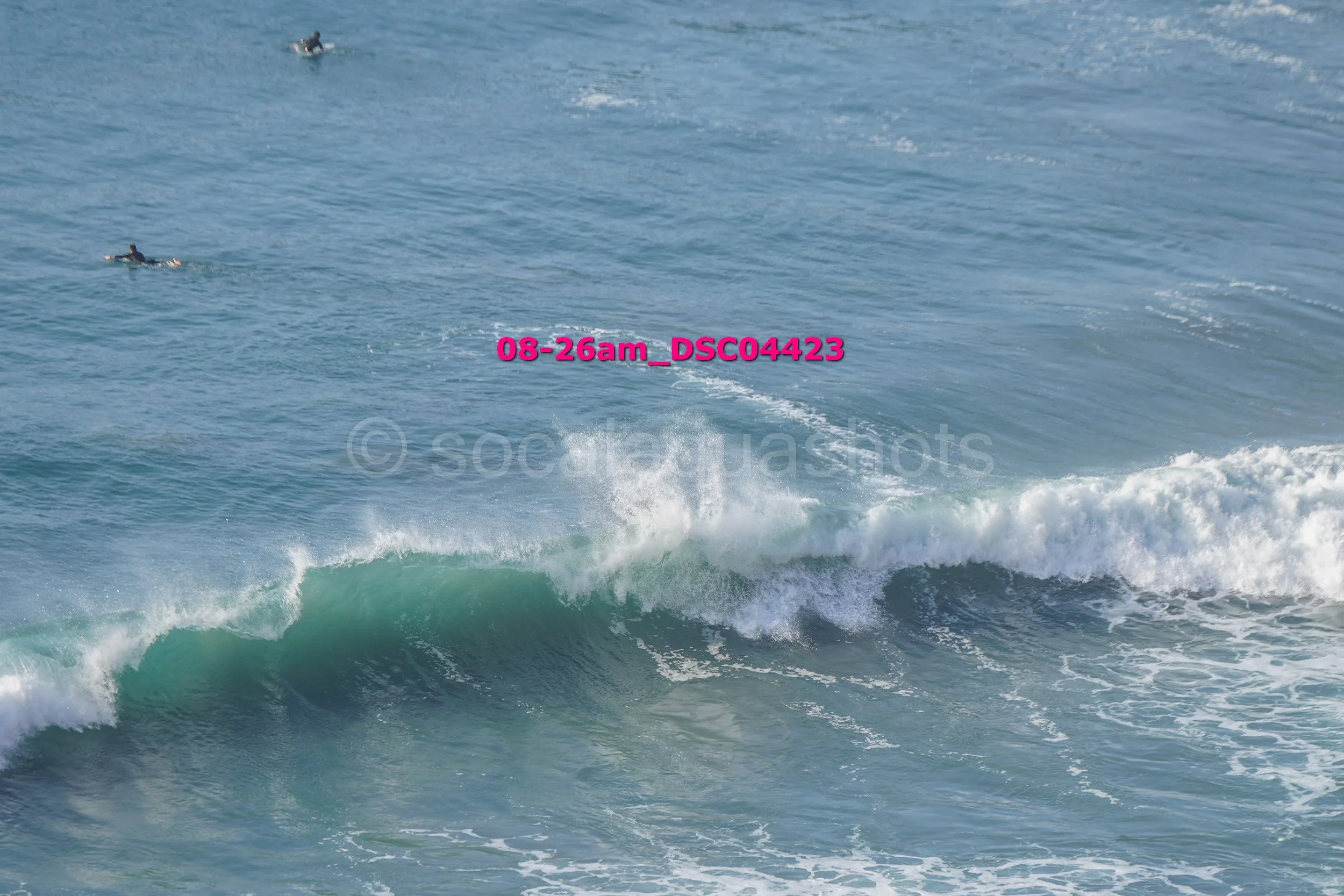 Ocean waves with surfers in the background. Text overlay reads '08-26am_DSC04423'.