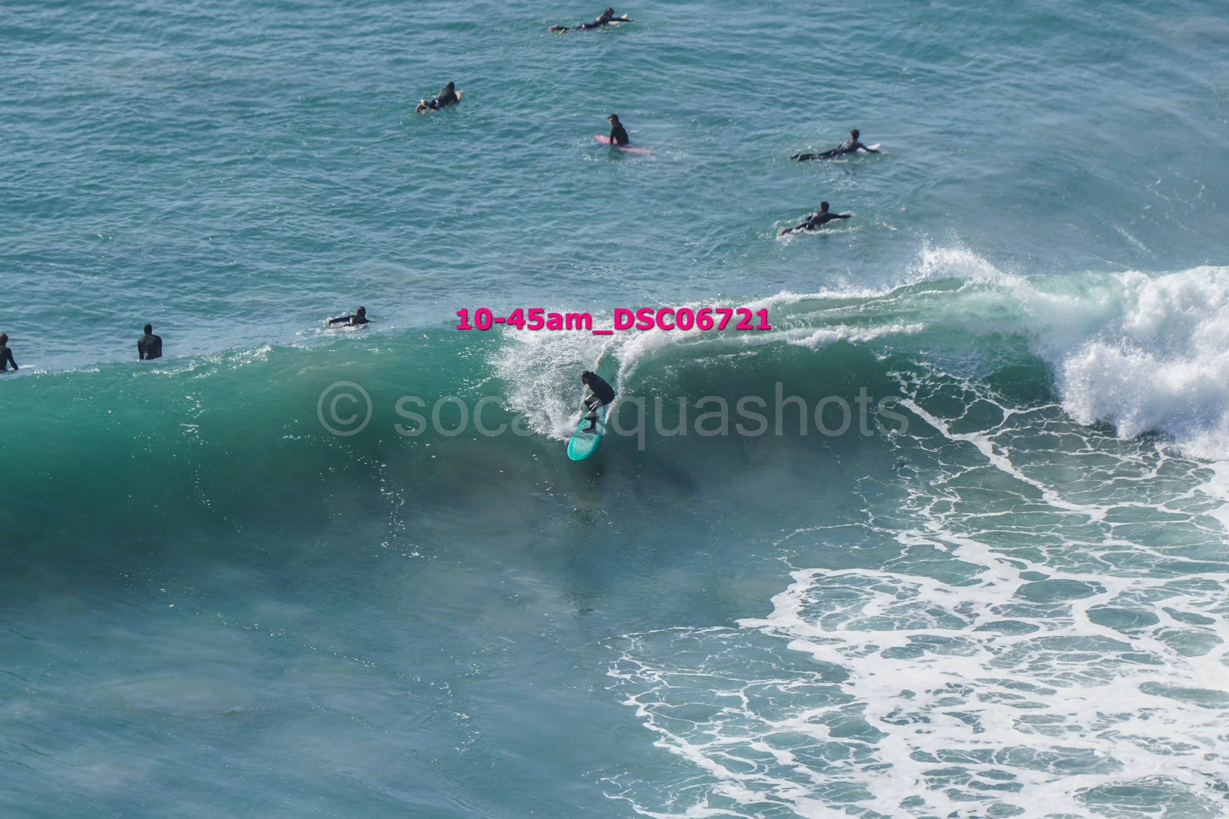 Surfer riding a large wave with several surfers in the water in the background.
