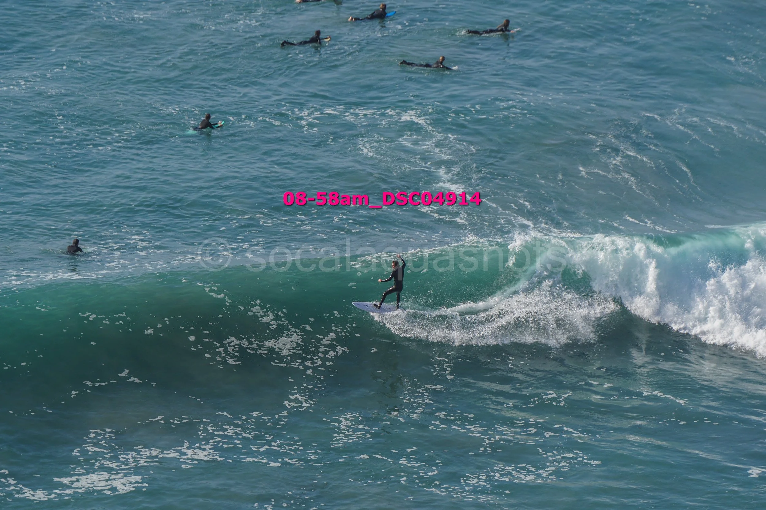 A person surfing on a wave with several surfers in the water around them.