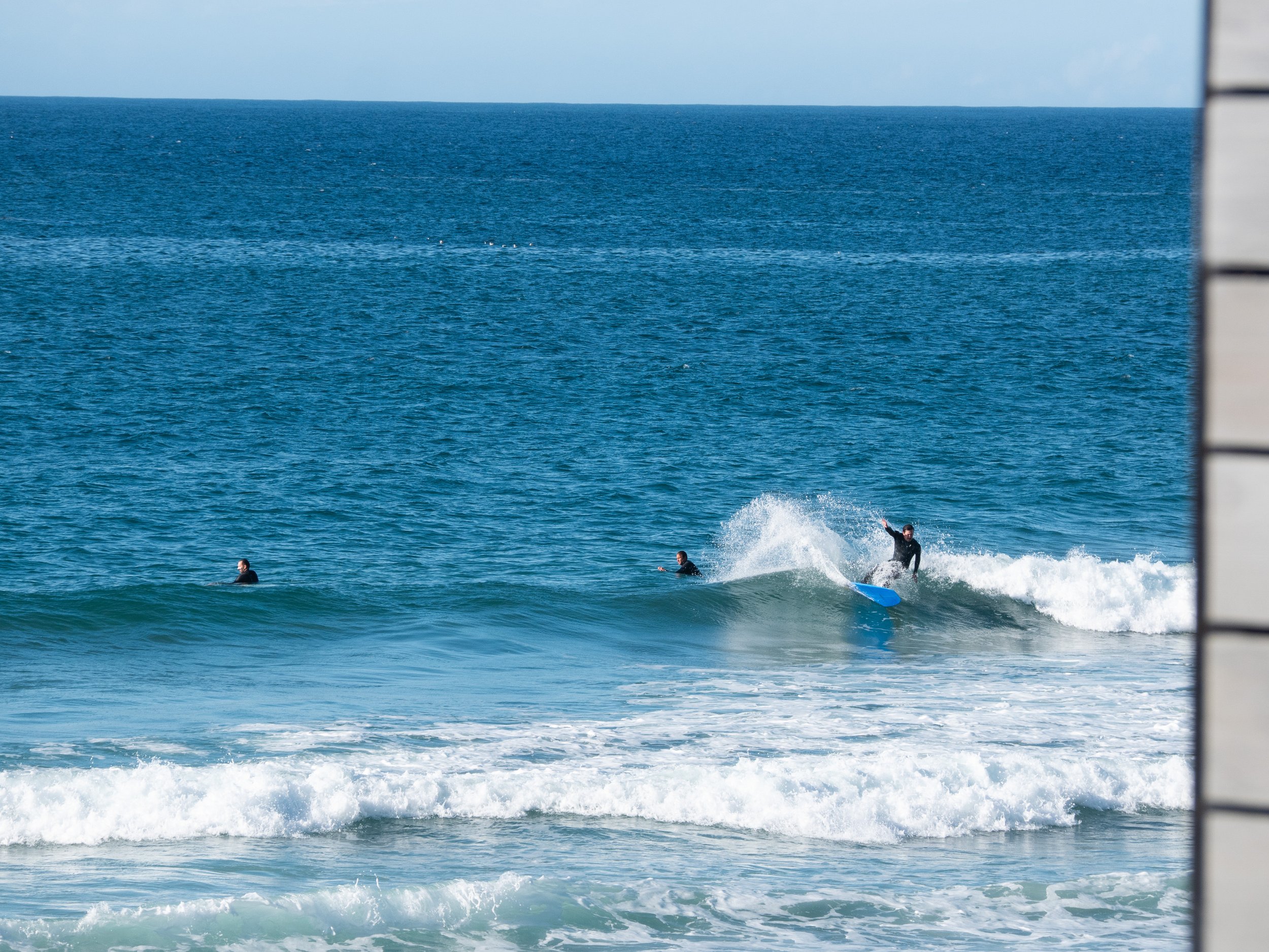 Surfers riding and waiting for waves at the beach.