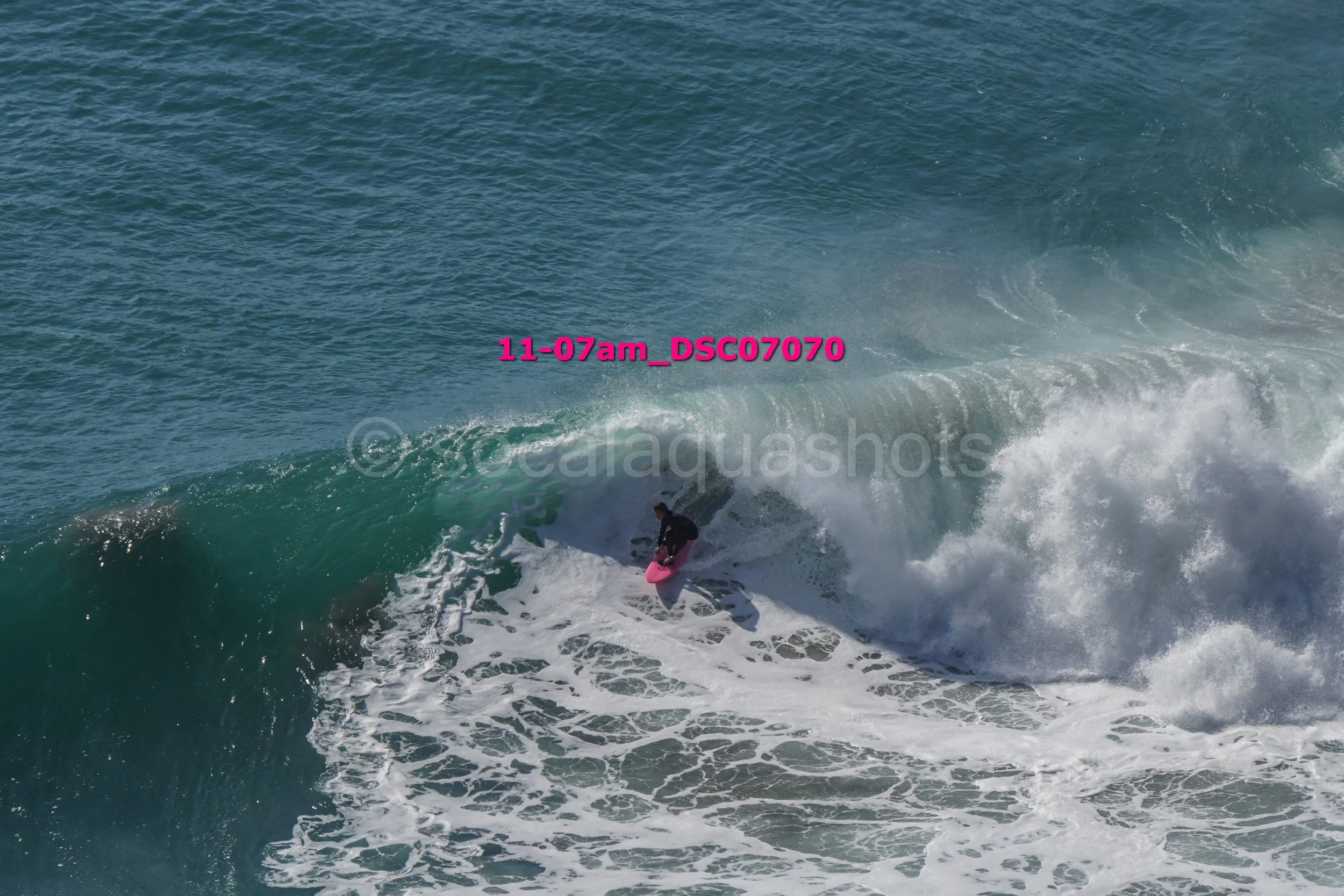 Surfer riding a wave on the ocean with white foam and a clear blue sky