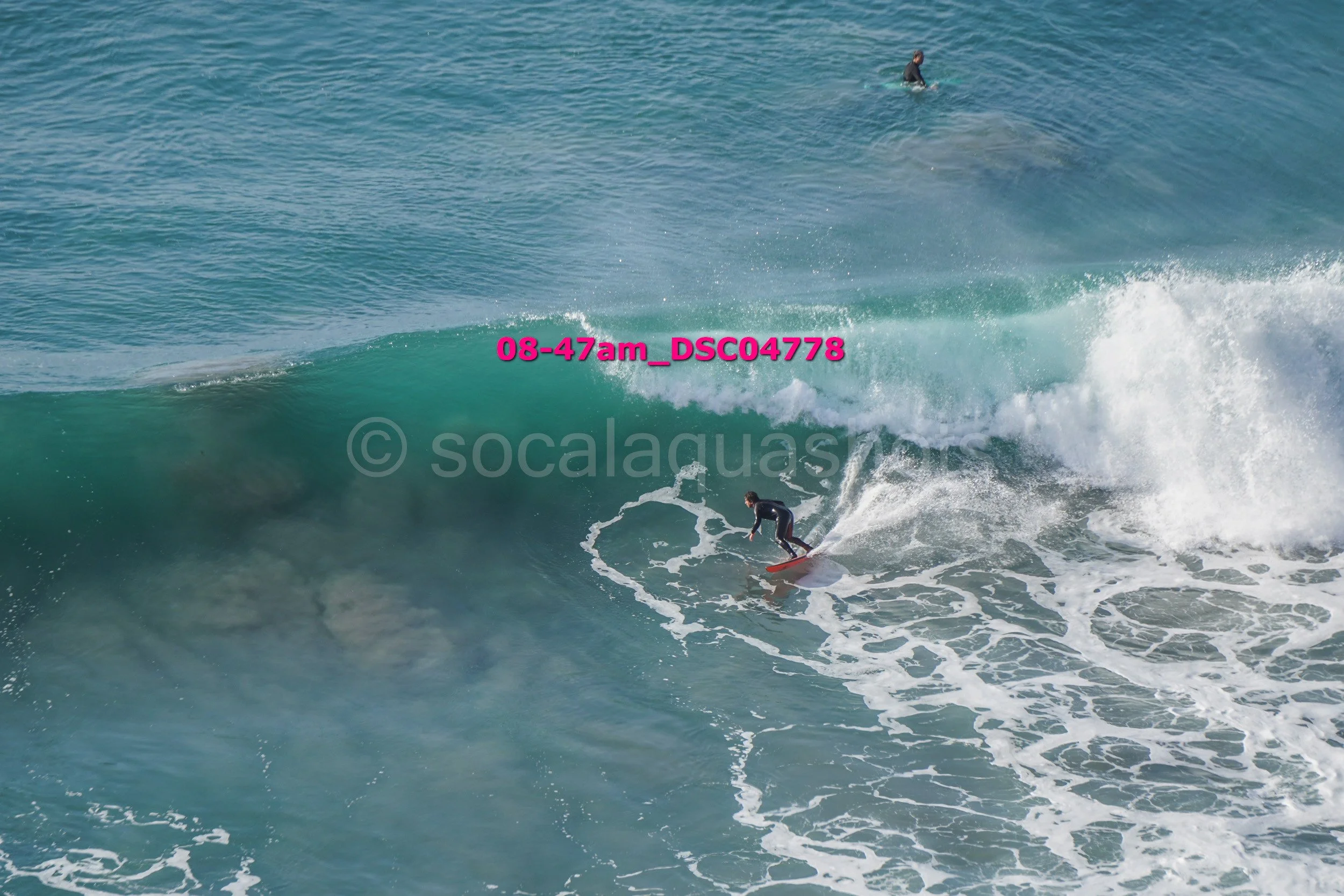 A surfer riding a wave with another surfer in the background in the ocean.