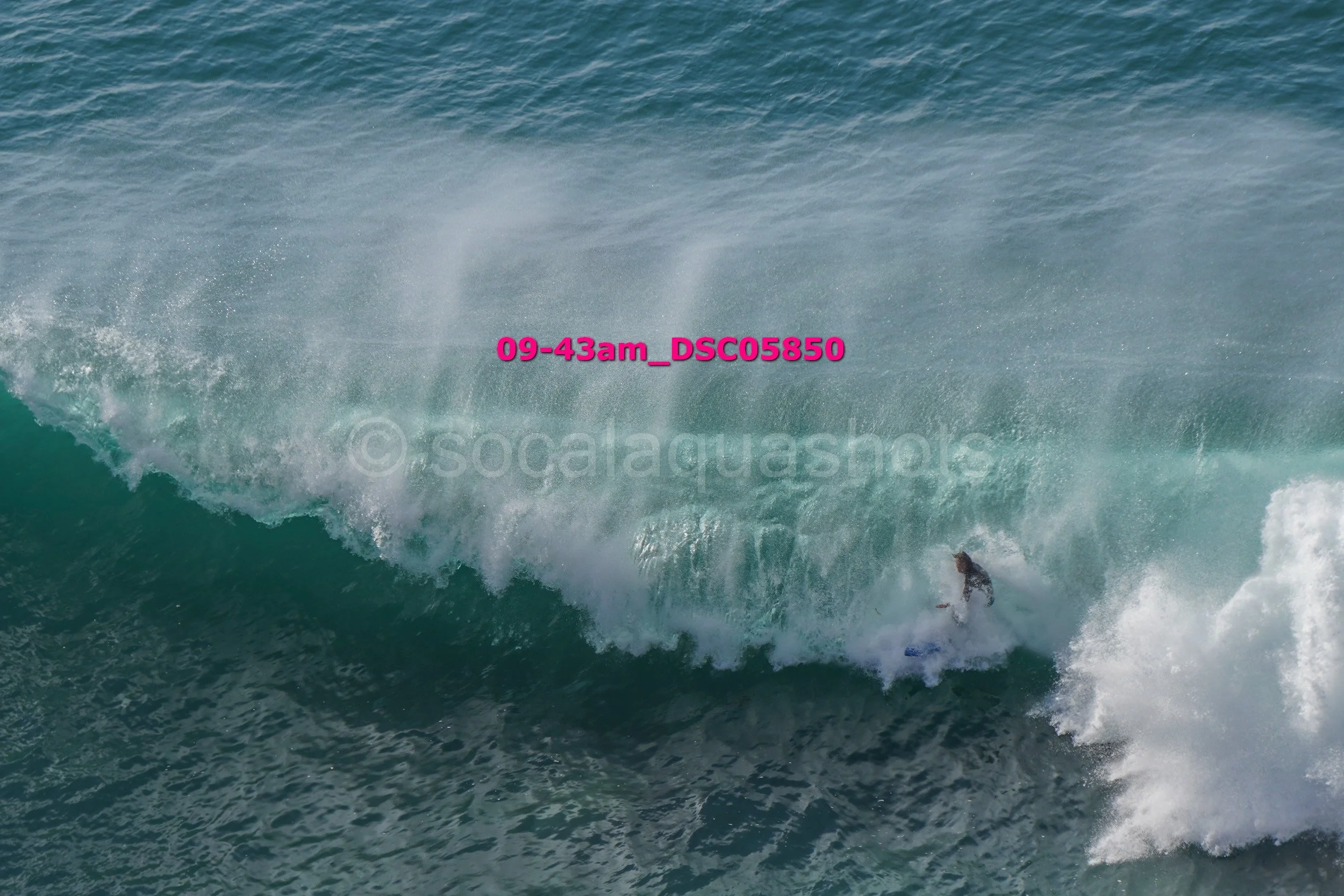 A person surfing on a large ocean wave during daytime.