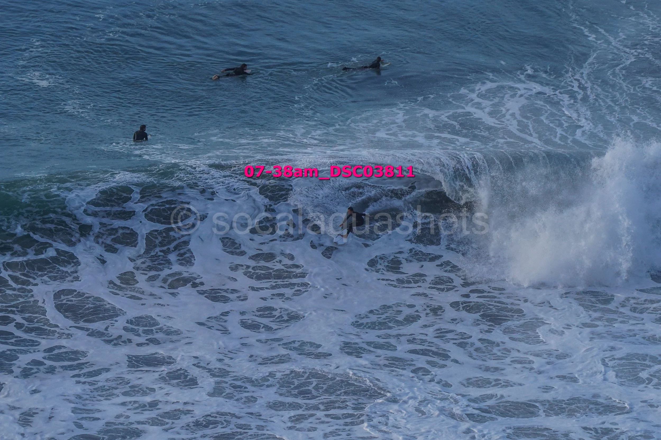 Several people swimming and surfing in the ocean waves.