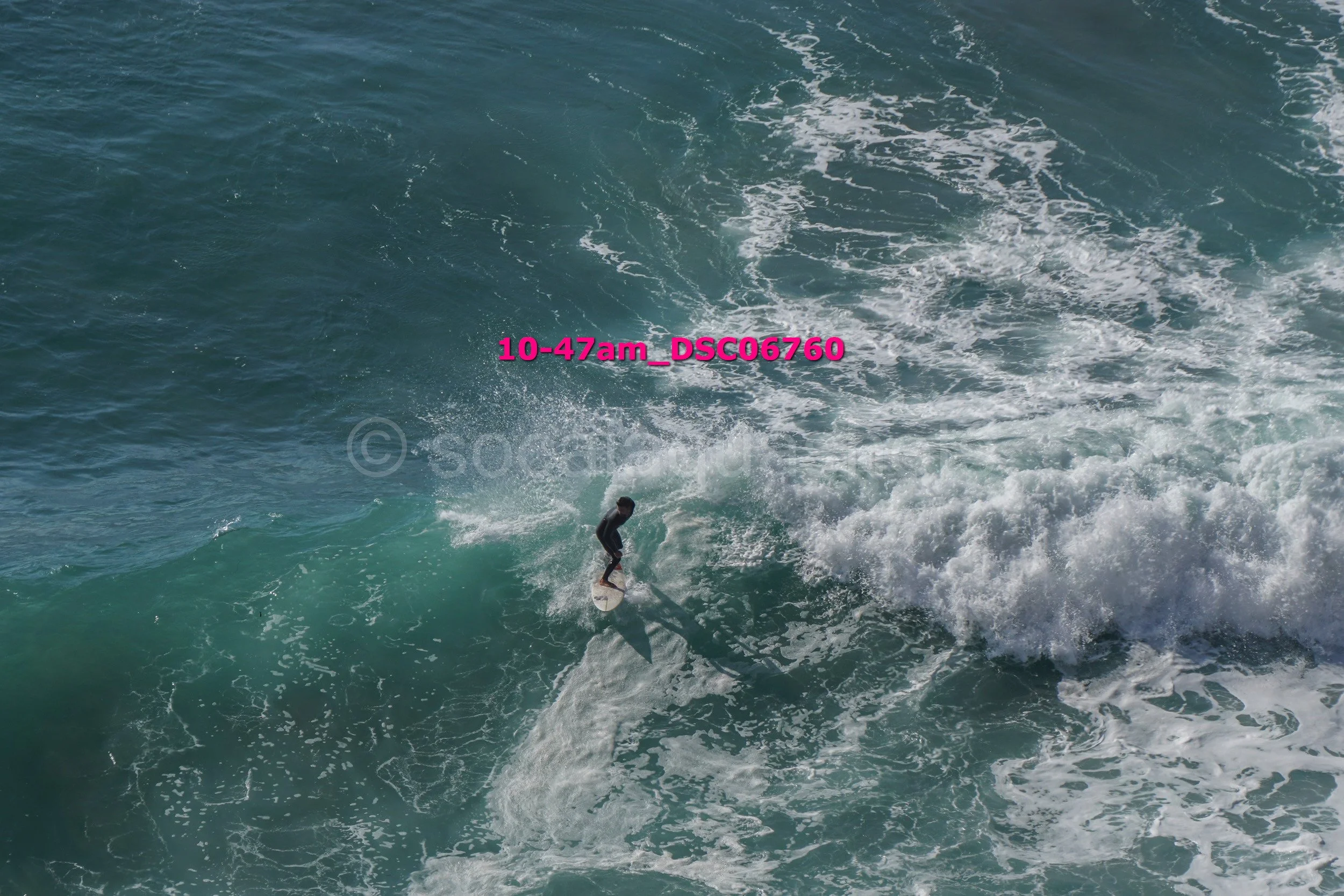 A person surfing on a large ocean wave during daytime.